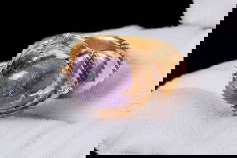 STUNNING HEAVY JAVANESE HIGH KARAT GOLD RING WITH AMETHYST CABOCHON: Ca. AD 600 - 900. A gold ring with gold pellets. The stepped hoop widens on the shoulders to form a floral-shaped bezel that secures the amethyst cabochon with four triangular points. For similar