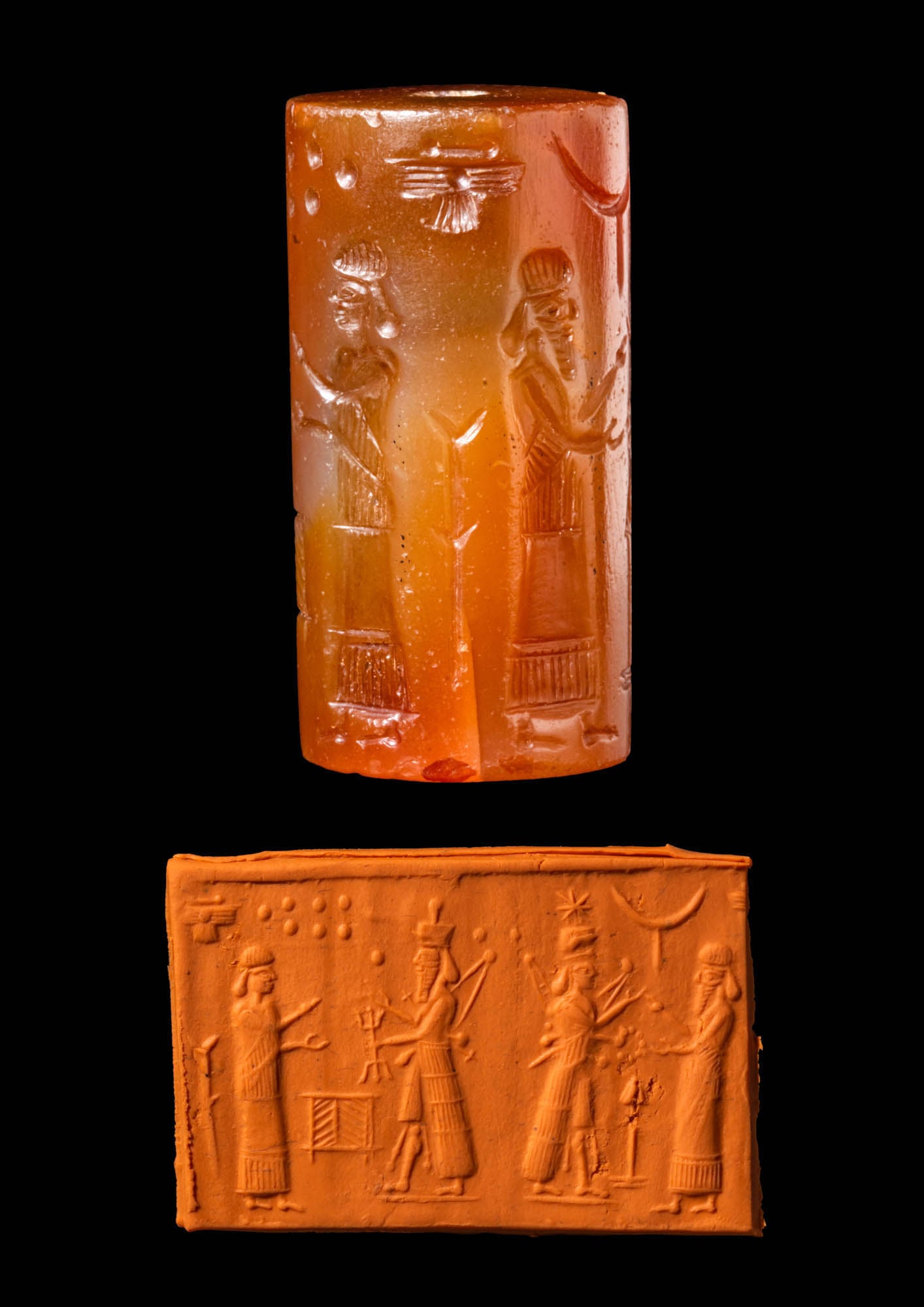 ASSYRO-BABYLONIAN CARNELIAN CYLINDER SEAL WITH WEATHER GOD: Ca. 8th - 6th century BC. A reddish stone cylinder seal depicting the weather god (Adad) and a worshipper, standing in front of an offering table. The spade of Marduk (patron deity of Babylon), the Pl