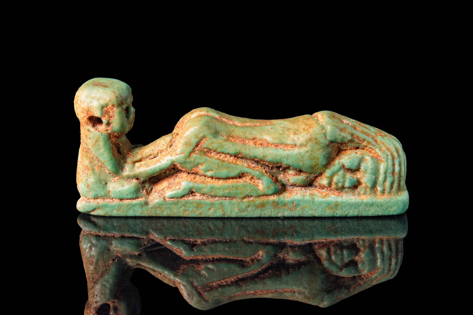 EGYPTIAN FAIENCE FERTILITY AMULET: Late Period to Ptolemaic Period, Ca. 664 - 30 BC. A faience fertility amulet modelled as a kneeling male figure positioned behind a prone female, her limbs bent beneath her body, both arranged horizon