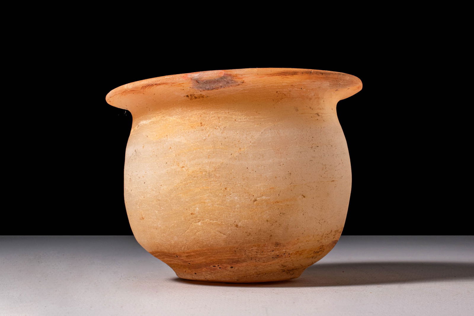 ROMAN PERIOD ALABASTER VESSEL: Ca. 30 BC - AD 200. An alabaster vessel with a rounded body tapering to a narrow, flat base and a wide, flat rim.Size: 110mm x 75mm; Weight: 380gProvenance: Private UK collection; previously acquired