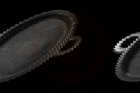 EGYPTIAN BLACK HARDSTONE OFFERING TRAY: Predynastic Period, Ca. 3100 - 2600 BC. A circular offering tray carved from dense black hardstone, with high straight walls rising from a flat base to a thick lip; opposed horizontal handles project