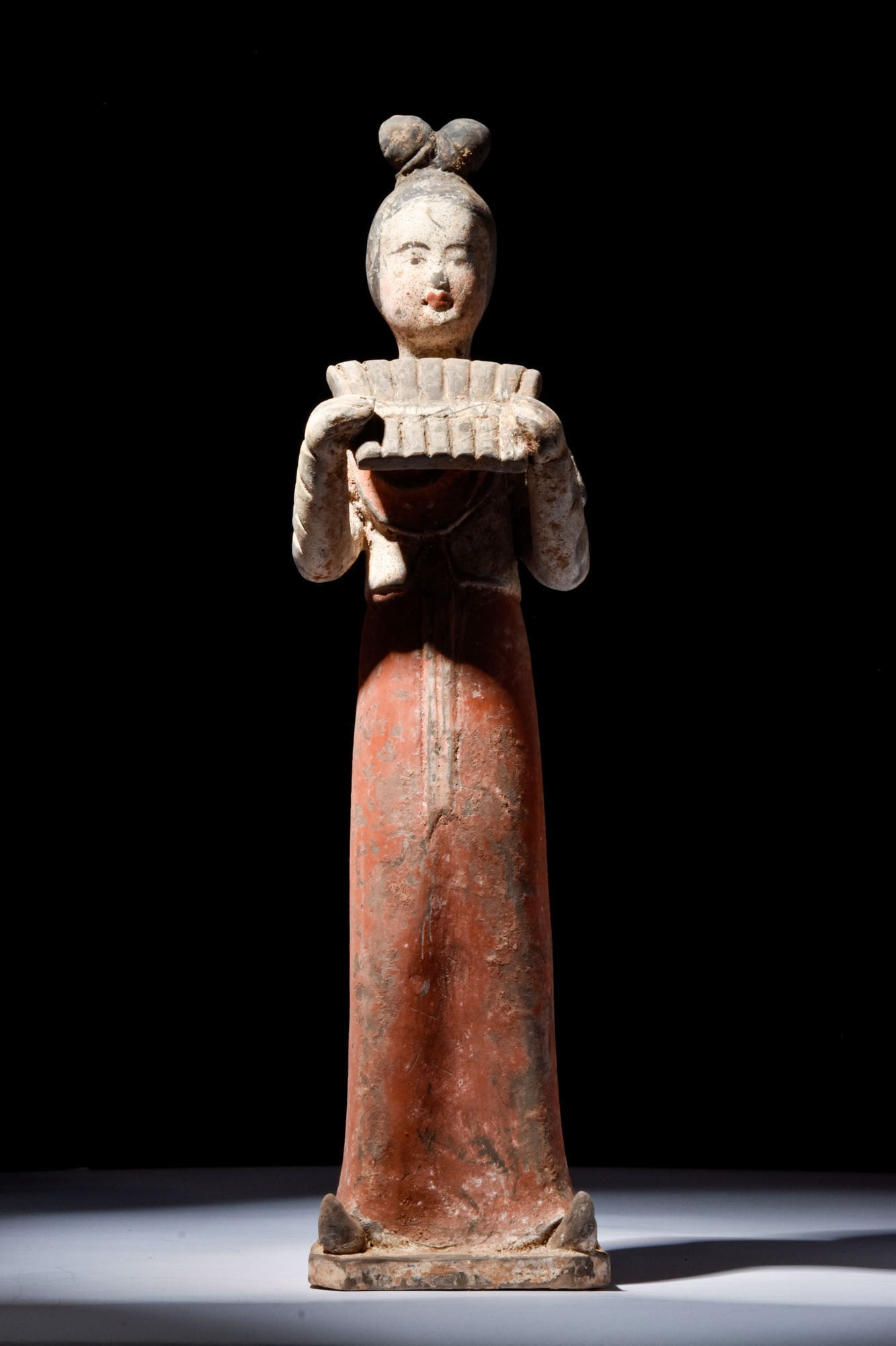 CHINESE TERRACOTTA FEMALE MUSICIAN - TL TESTED: Tang Dynasty, Ca. AD 618 - 907. A terracotta female musician standing upright with long flowing robes, a short over-jacket, and high, coiffed hair, with painted eyes and lips, holding a pan flute clos