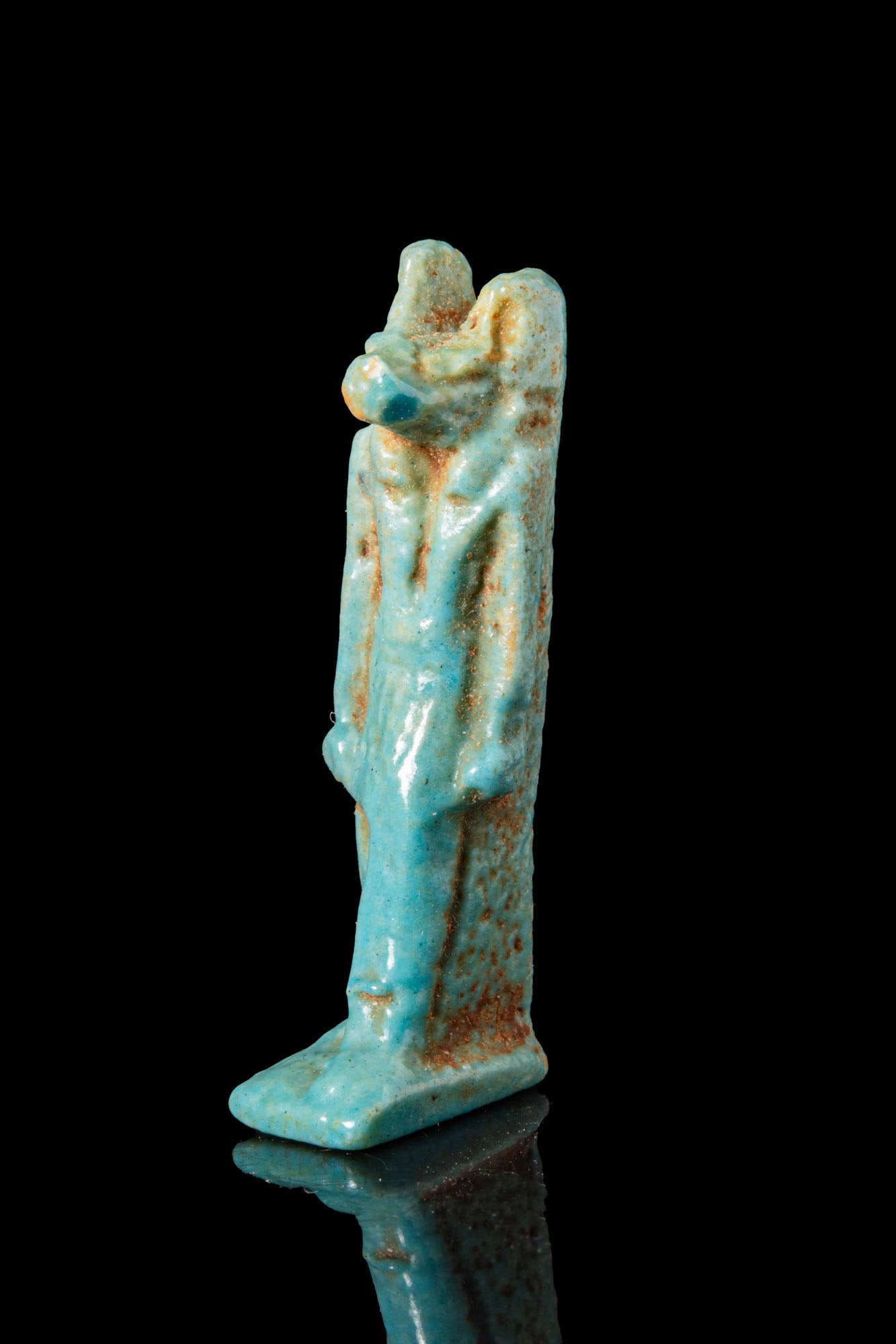 EGYPTIAN FAIENCE ANUBIS AMULET: Third Intermediate Period, Ca. 1069 - 664 BC. A faience amulet of Anubis standing on a small rectangular base. The jackal-headed god has an elongated muzzle and upright ears, wears a pleated kilt, and
