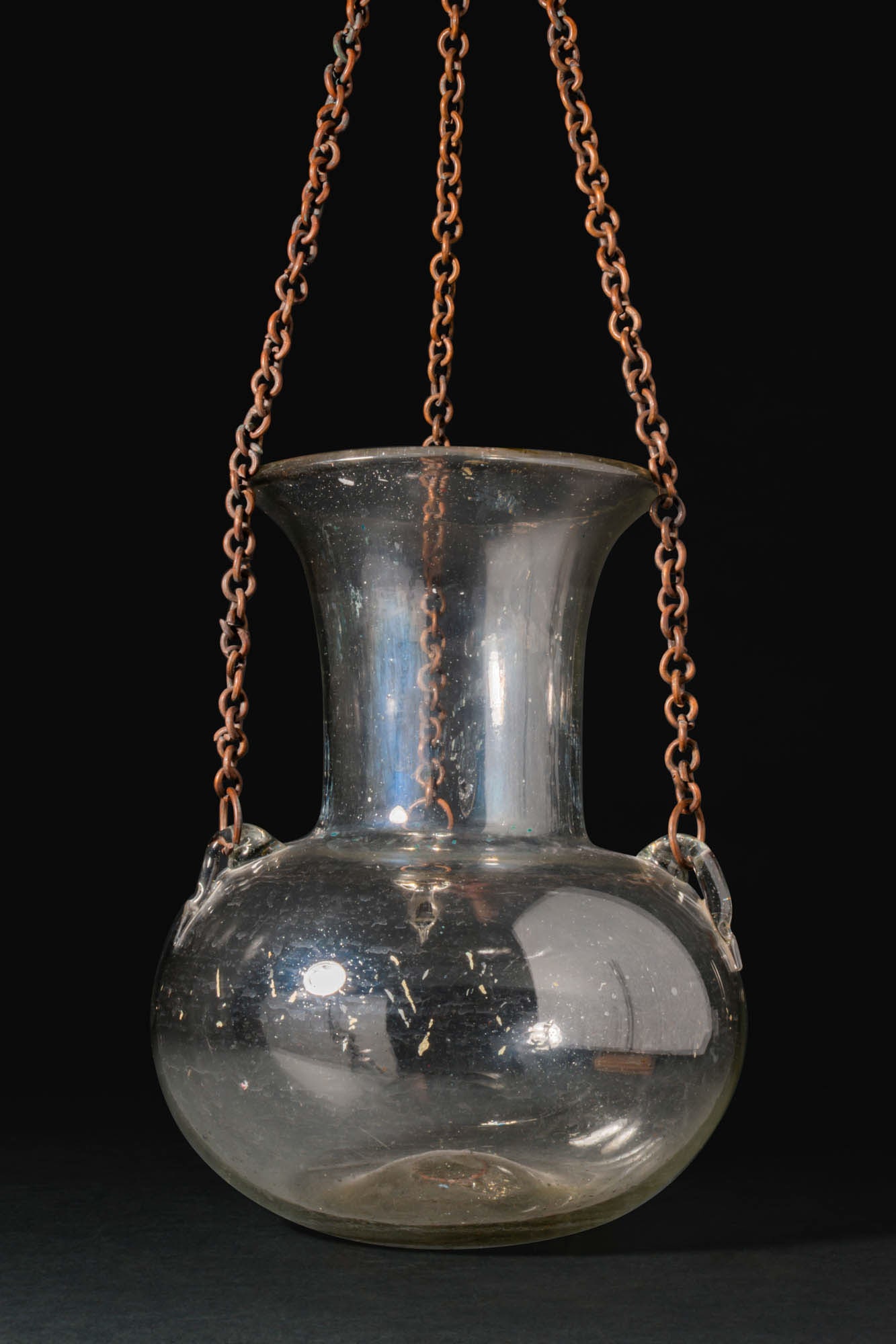 REVIVAL GLASS MOSQUE LAMP: Ca. 20th century AD. A glass mosque lamp of colourless glass with a globular body on a concave base, rising to a tall, flaring neck with a broad everted rim. Three small applied loop handles are set a