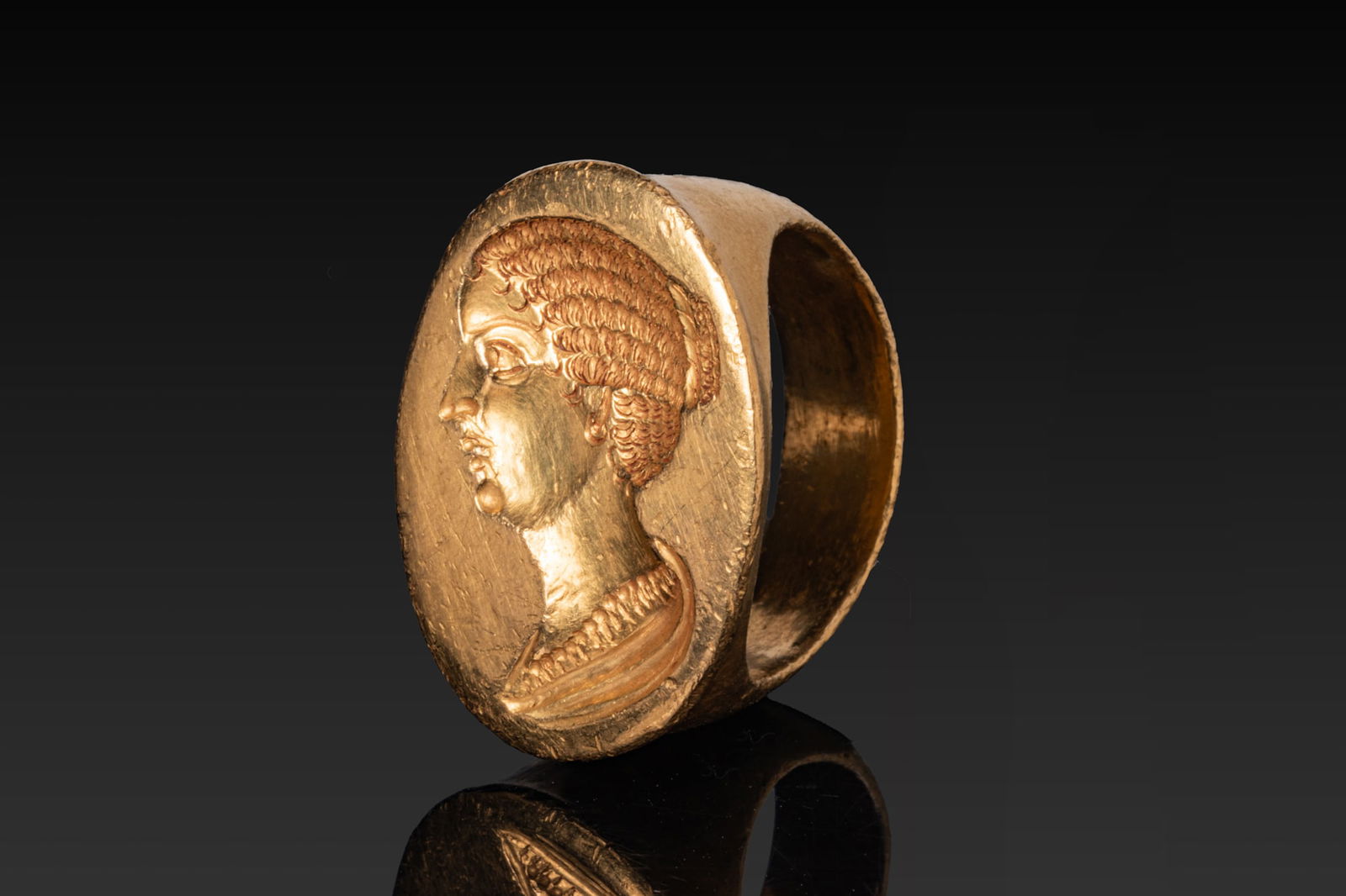 HUGE ROMAN HIGH KARAT GOLD RING WITH BUST OF FAUSTINA THE YOUNGER: Ca. AD 150 - 200 A rare and beautiful 23kt gold ring with a broad oval bezel engraved with the draped bust of Faustina the Younger in left profile, with finely modelled facial features and the hair ar