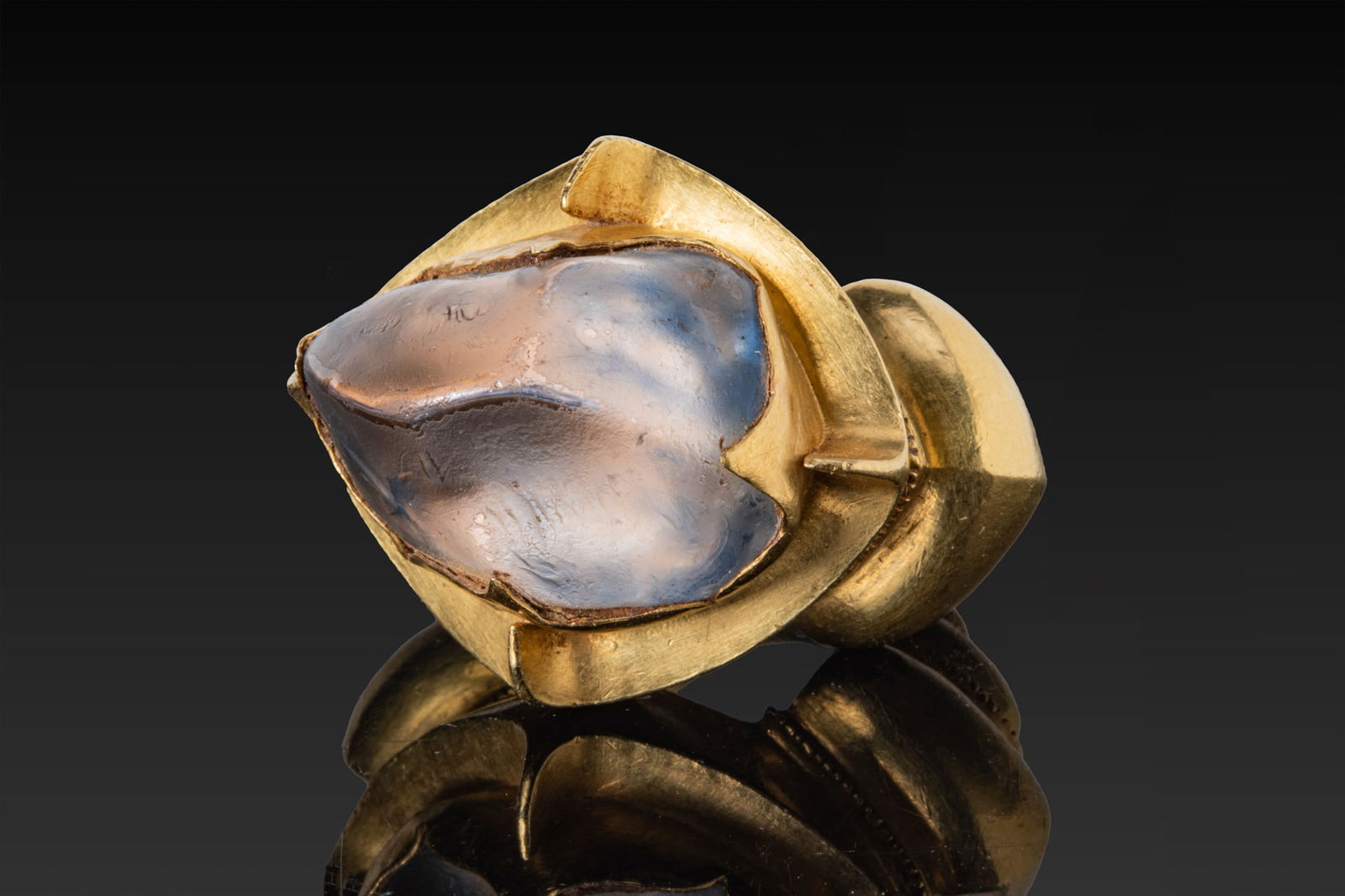 IMPORTANT JAVANESE SOLID HIGH KARAT GOLD RING WITH LARGE SAPPHIRE - 34 GRAMS: Ca. AD 700 - 1000 A gold ring with a massive bezel rising from a stepped, lobed hoop. The bezel plate of cusped lozenge outline is fitted with four upstanding triangular prongs framing a large sapphir