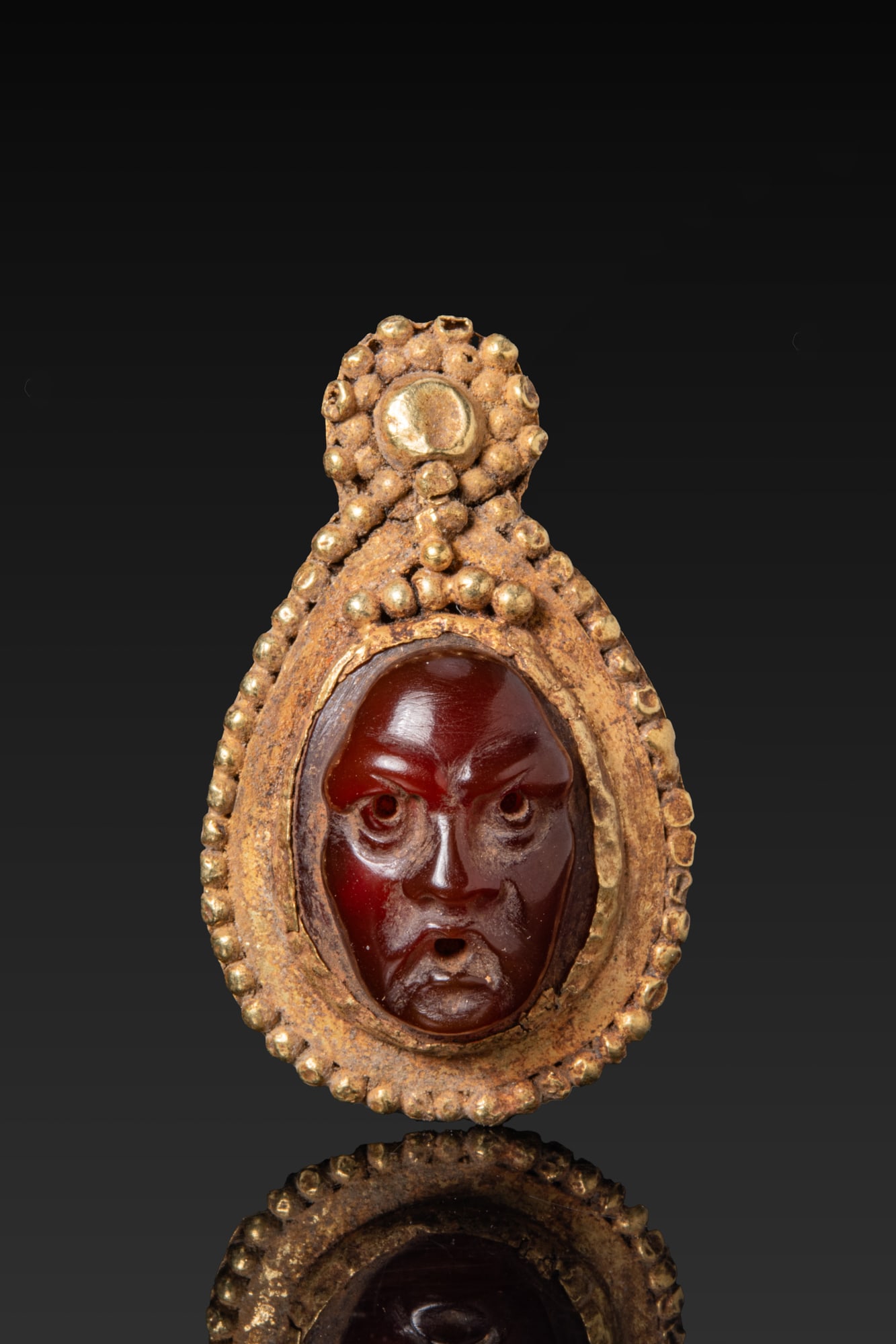 ROMAN HIGH KARAT GOLD DROP-SHAPED PENDANT SET WITH A CARNELIAN HEAD OF A THEATRE ACTOR (1 of 3)