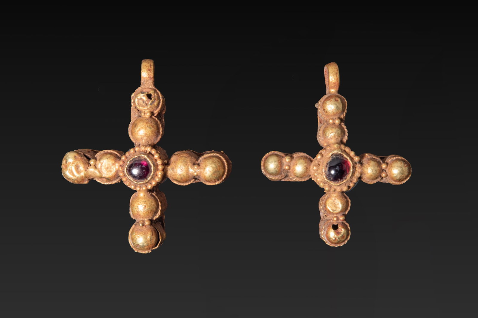 PAIR OF BYZANTINE HIGH KARAT GOLD CROSS PENDANTS WITH CENTRAL CABOCHON: Ca. AD 600 - 800 A pair of gold pendants with central cabochons, each composed as a cross of eight globular elements forming the arms, with a beaded circular bezel at the junction set with a red garne