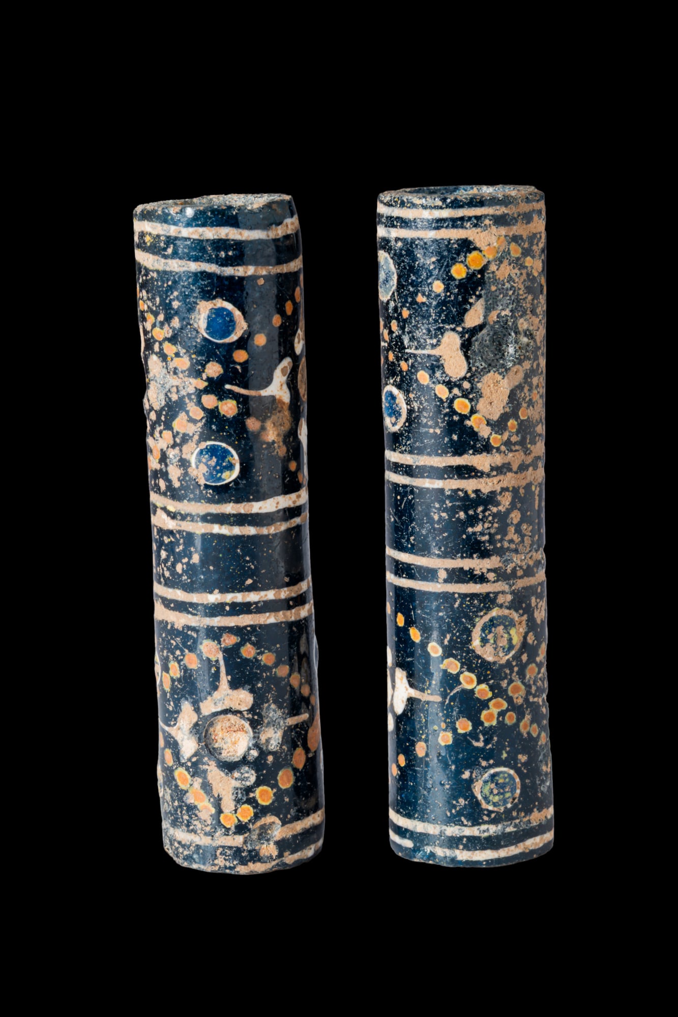 PAIR OF CHINESE WARRING STATES GLASS CYLINDRICAL BEADS: Ca. 475 - 221 BC A pair of dark blue glass cylindrical beads, each pierced lengthwise and decorated with four white double bands, one near each end and two in the central area. The double bands divide