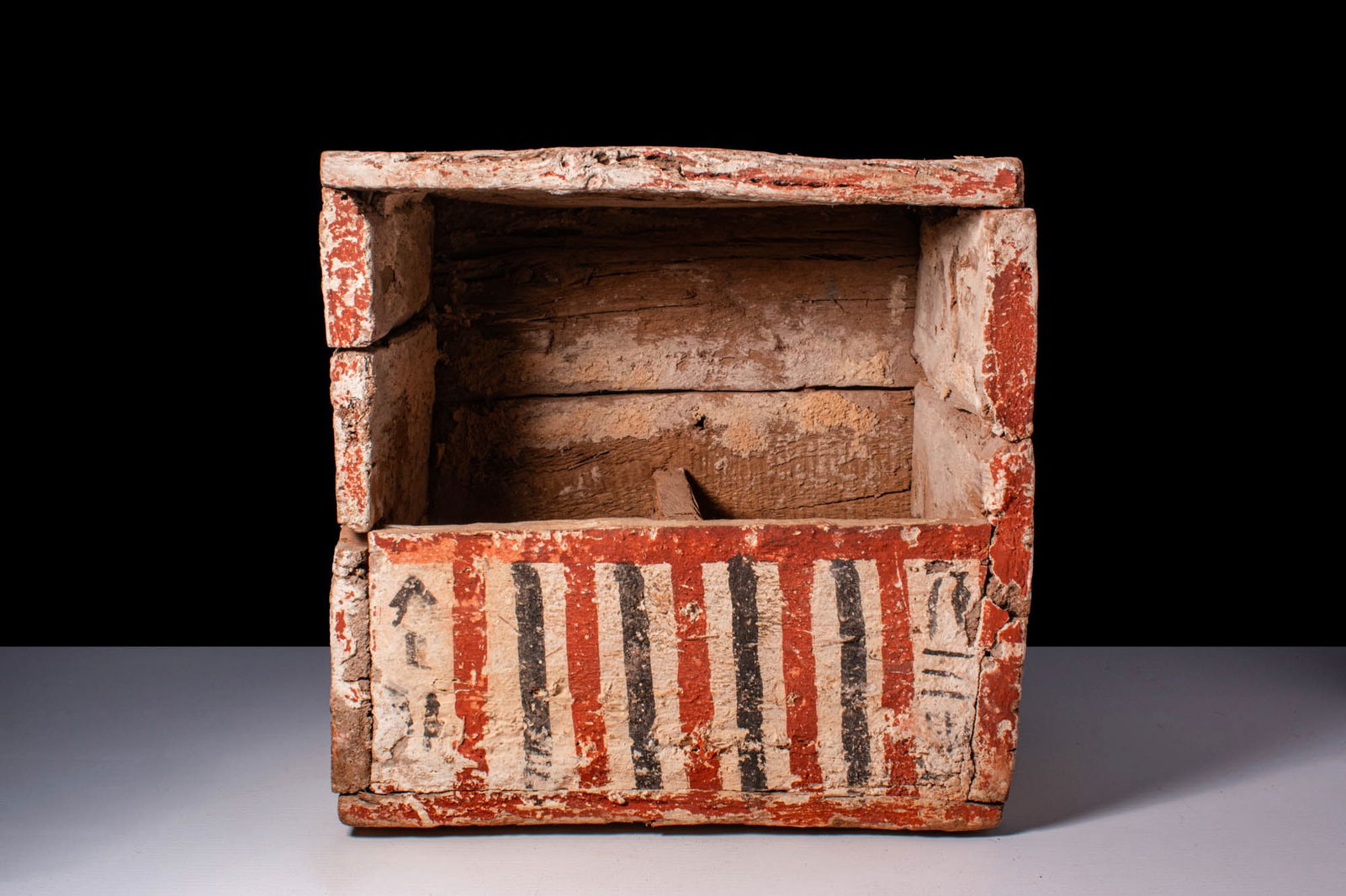 EGYPTIAN PAINTED WOOD USHABTI CASE WITH PAPYRUS FLOWERS: New Kingdom, Ca. 1550 - 1069 BC. A rectangular wooden ushabti case constructed from fitted planks with a flat top and base. The front is painted with alternating vertical stripes in black and white