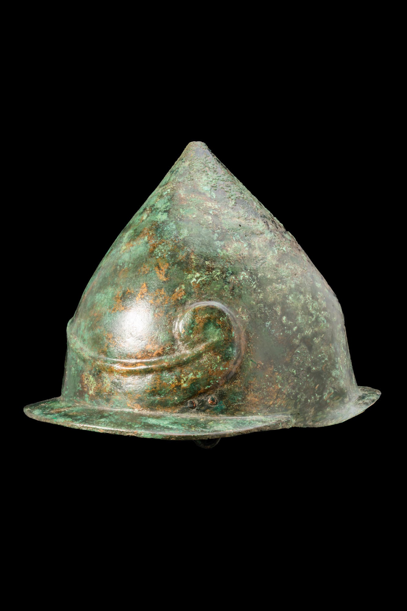 RARE GREEK KONOS TYPE BRONZE HELMET: Ca. 300 - 100 BC A bronze pilos helmet with a tall conical skull rising to a pointed apex and encircled by a broad brim. At the front a moulded ridge forms an upward-pointing chevron on the brow and