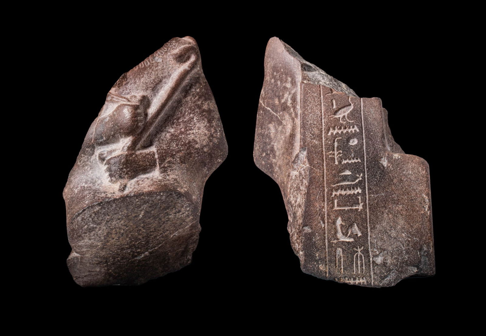 EGYPTIAN DIORITE STATUETTE OF PHARAOH WITH HIEROGLYPHIC INSCRIPTION: Third Intermediate Period, Ca. 1069 - 664 BC. A fragment of a dark diorite statuette depicting the upper body of a pharaoh, shown holding a crook in the left hand and a flail in the right. Traces of