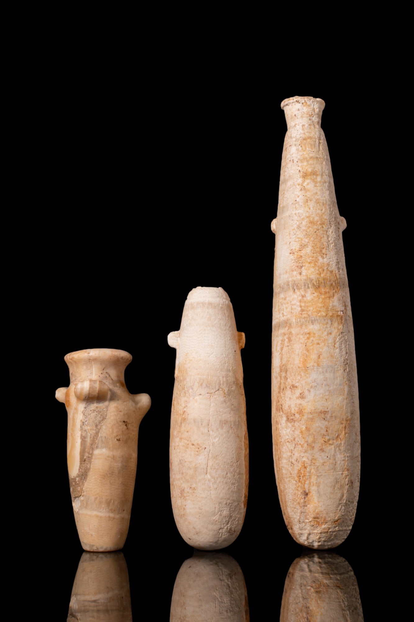COLLECTION OF THREE EGYPTIAN ALABASTRA: Late Period, Ca. 664 - 332 BCA collection of three alabaster alabastra, including, from left to right: a small vessel with a slightly tapering cylindrical body, flaring discoid rim and rounded