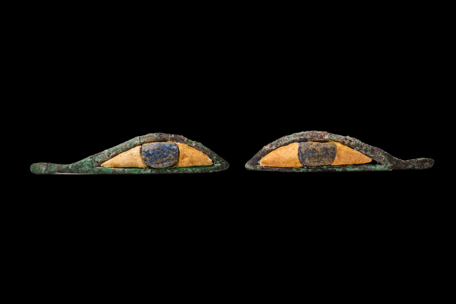 PAIR OF EGYPTIAN BRONZE AND STONE INLAID EYES: Late Period, Ca. 664 - 332 BCA pair of inlaid eyes formed as elongated bronze frames with pointed inner and outer corners, each set with a yellowish stone sclera and a convex blue stone iris.Size: