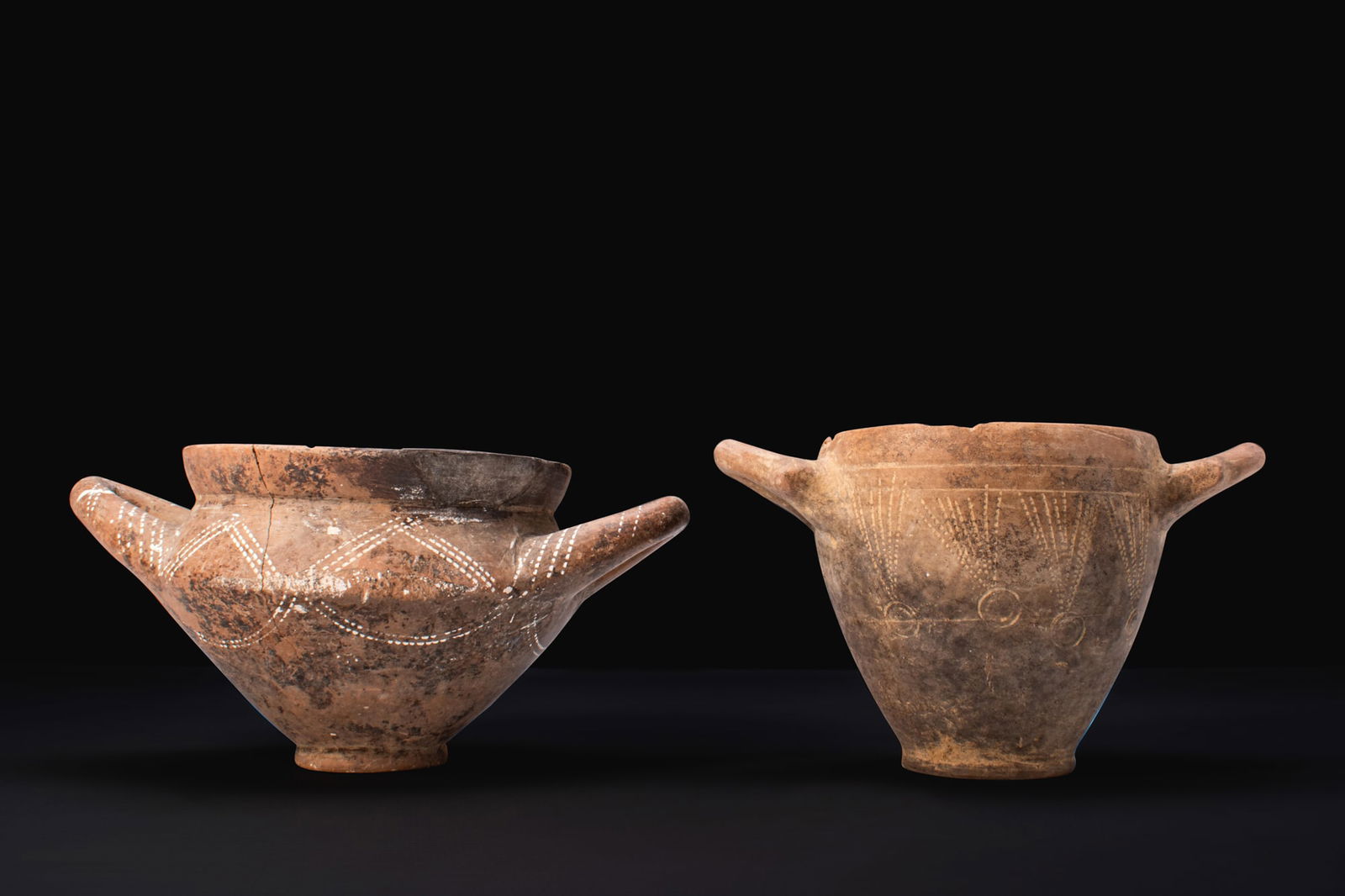 PAIR OF VILLANOVAN DECORATED VESSELS: Ca. 900 - 700 BCA pair of impasto vessels, including, from left to right: a cup with a wide everted rim and compressed profile, fitted with a pair of opposed handles, decorated around the shoulder