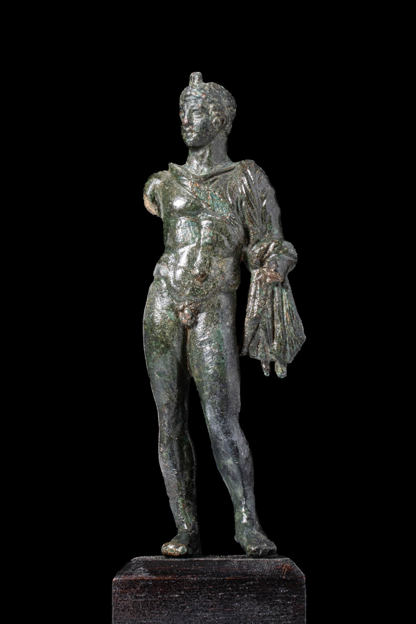 STUNNING ROMAN BRONZE FIGURINE OF MERCURY: Ca. AD 1 - 200. A bronze figurine representing a nude male figure identified as god Mercury, depicted standing with weight on the right leg and the left slightly advanced. A chlamys is draped over his