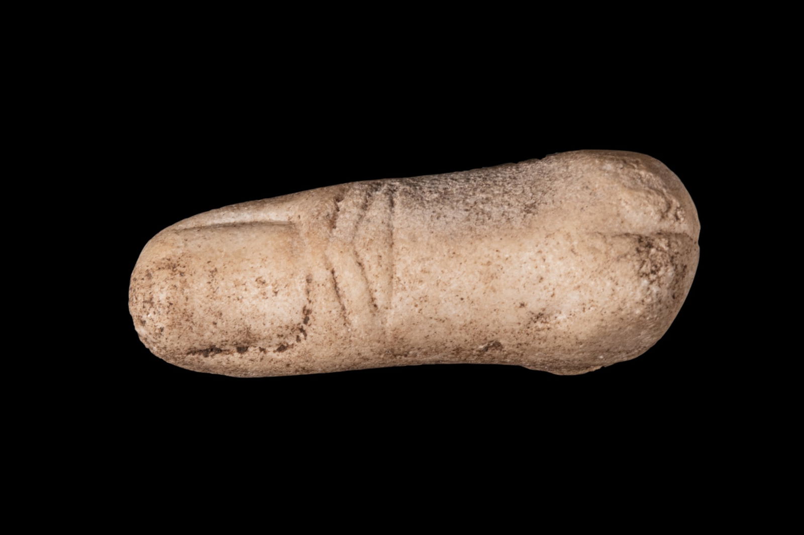 ROMAN MARBLE THUMB EX VOTO: Ca. AD 1 - 300A marble anatomical votive carved as a thumb, shown slightly bent with the nail indicated by an incised border and the interphalangeal crease marked by diagonal grooves. The finger taper