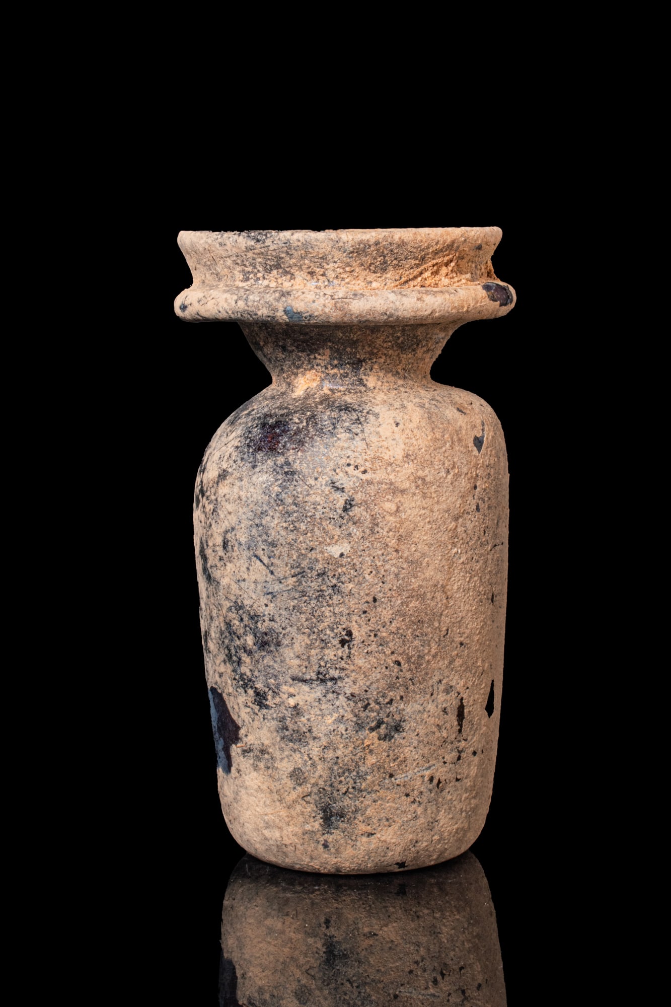 ROMAN GLASS BOTTLE: Ca. AD 300 - 500An aubergine-coloured glass bottle with a tall cylindrical body above a concave base. The shoulder slopes to a funnel-shaped neck surmounted by a pronounced horizontal collar and