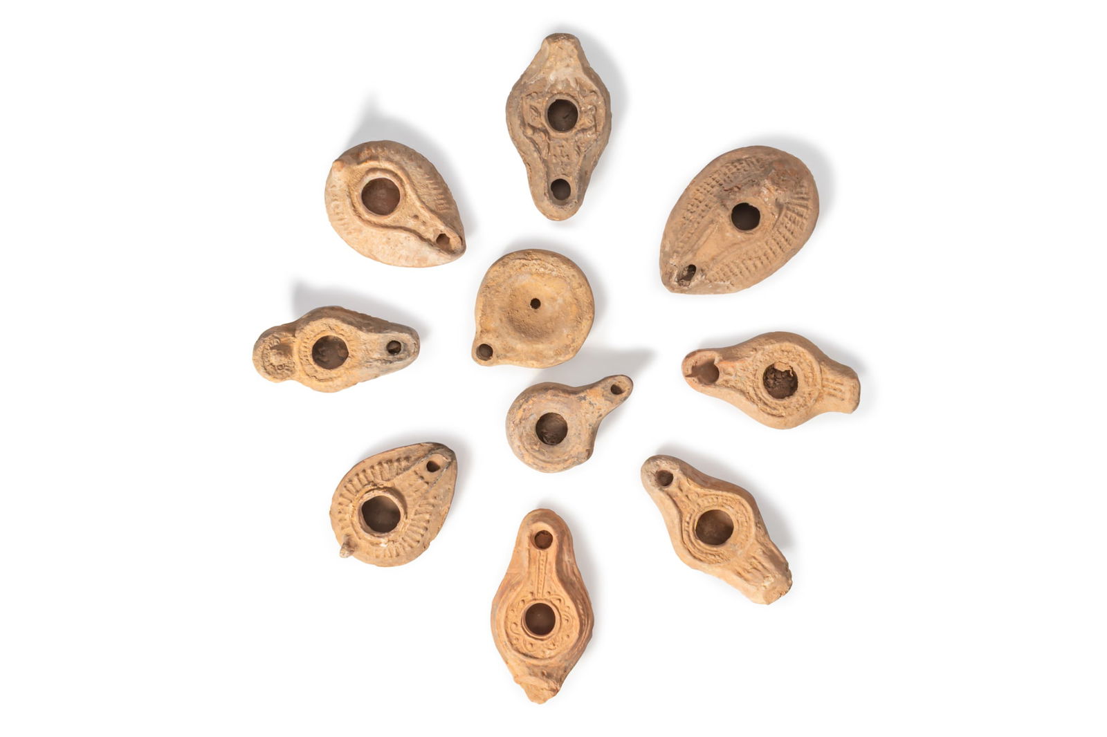 COLLECTION OF ROMAN AND BYZANTINE TERRACOTTA OIL LAMPS: Ca. AD 200 - 600A collection of ten terracotta oil lamps, each with a drop-shaped or circular body and a recessed central filling hole within a raised rim. The shoulders have moulded decoration,