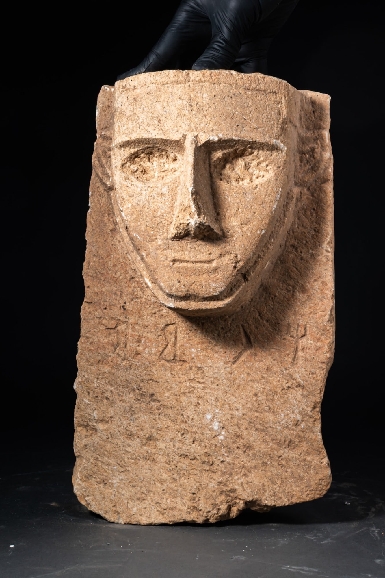 SOUTH ARABIAN STONE STELA WITH INSCRIPTION: Ca. 300 - 100 BC This South Arabian stela in buff calcareous stone is dominated by a projecting ?hula?- style face carved in high relief, its features strongly schematised, with heavy brows, deep-set