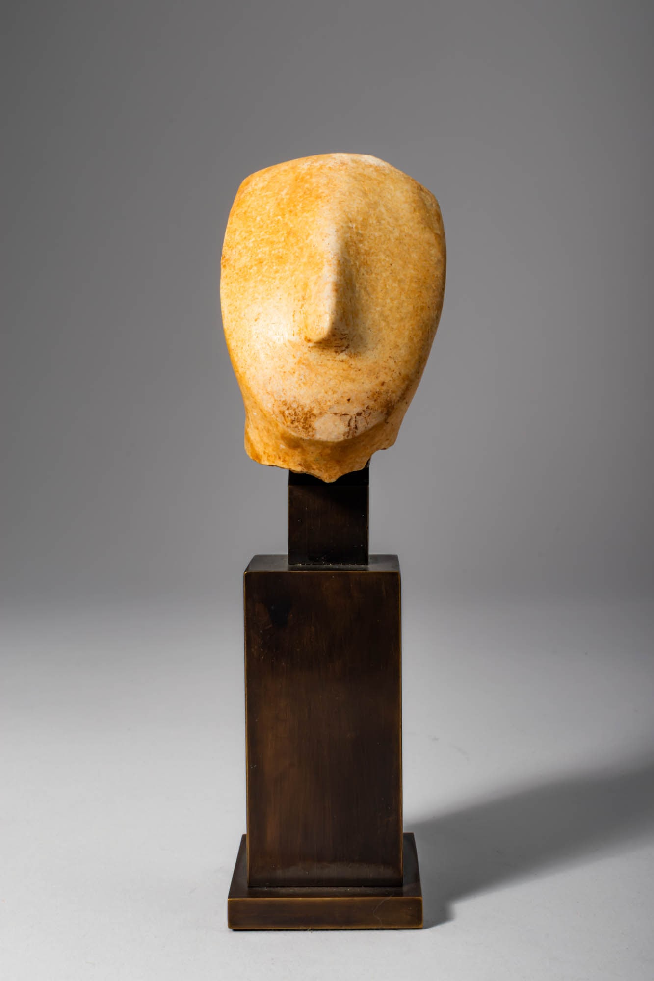 CYCLADIC MARBLE IDOL HEAD: Ca. 2500 - 2200 BC Cycladic marble idol head, schematically carved and characterised by an elongated oval face and a prominent triangular nose formed in high relief. The facial features are reduced to