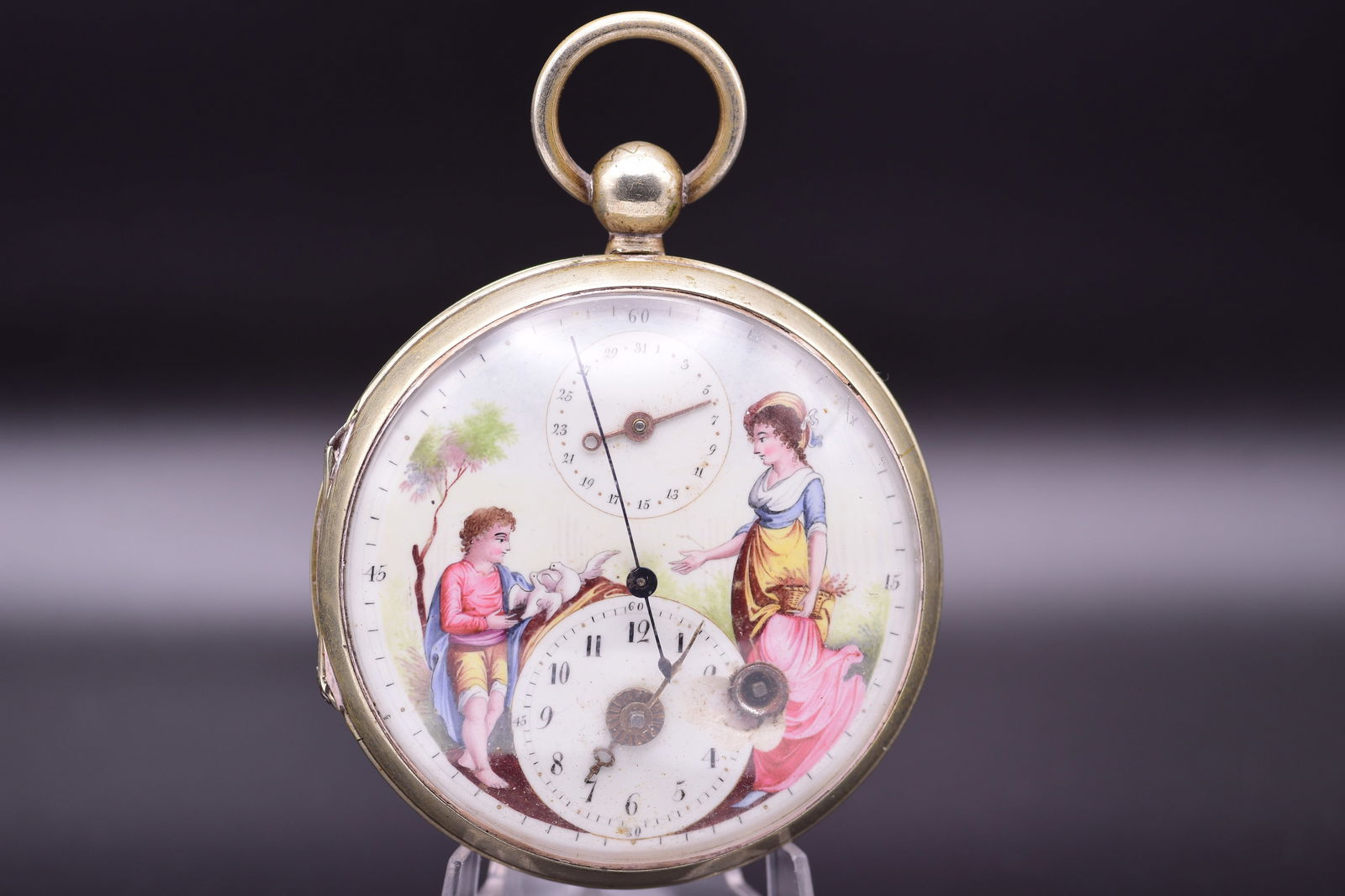 A Fine George III Enamel Painted Dial Verge Fusee Central Seconds Calendar Complication Pocket Watch: C. 1810BAn exquisite and rare Georgian verge fusee pocket watch, circa 1810, crafted in gilt with a masterfully hand-painted enamel dial depicting a charming allegorical scene. This superb example of