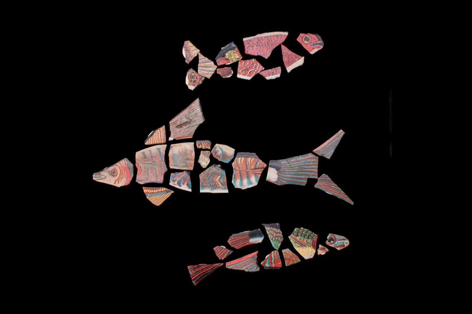 COLLECTION OF THREE EGYPTIAN MOSAIC GLASS FRAGMENTARY FISH INLAYS - EX CHRISTIE'S - EX GROPPI: Ca. 100 BC - AD 100. A collection of three fragmentary mosaic glass fish inlays, each composed of polychrome cane segments simulating heads, bodies, fins and tails in red, blue, green, yellow and whit