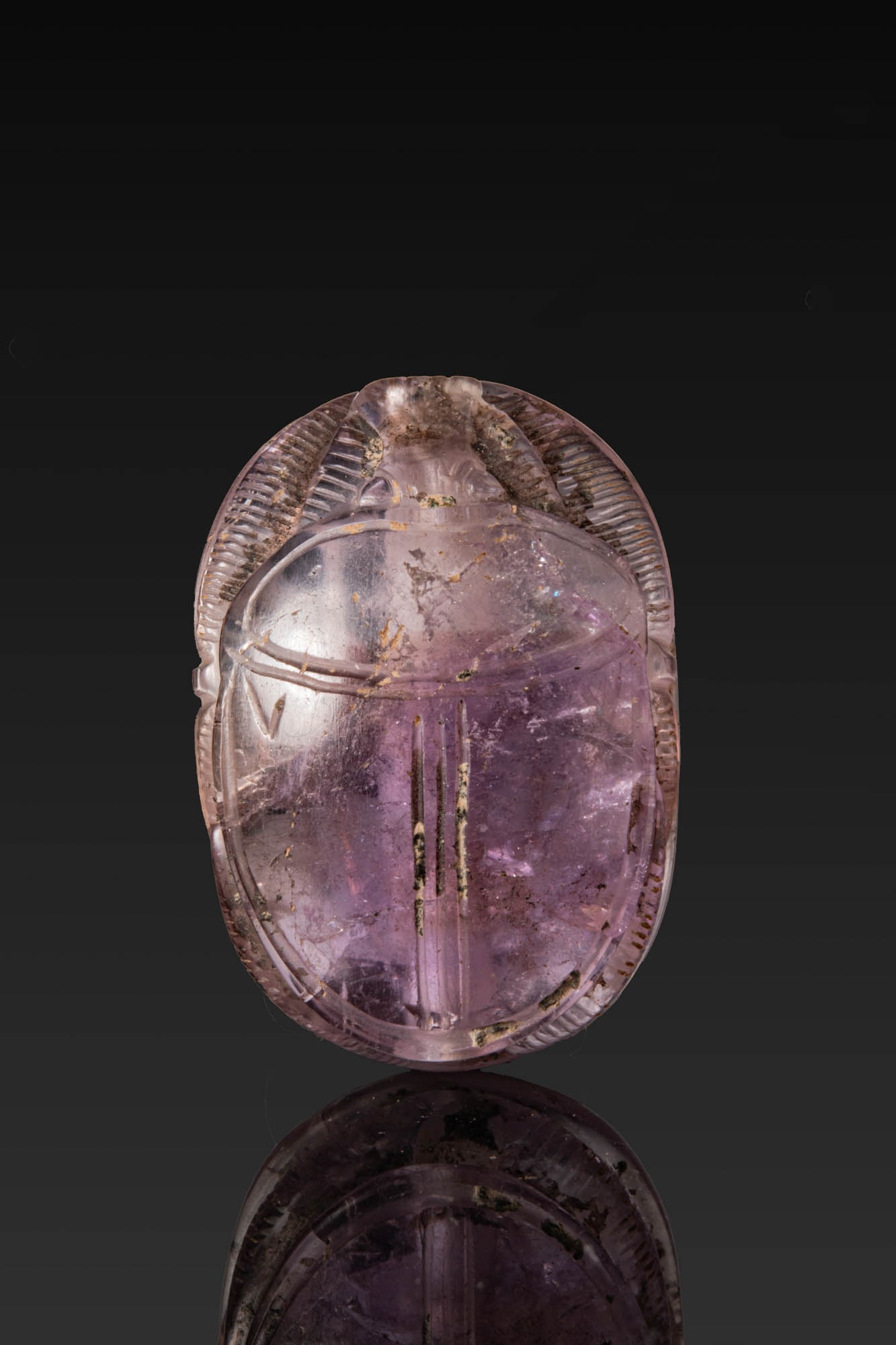 EGYPTIAN AMETHYST SCARAB: New Kingdom, Ca. 1550 - 1069 BC. An amethyst scarab with lengthwise perforation. The domed back with a broad prothorax and the wing cases divided by three longitudinal grooves, the small head flanked