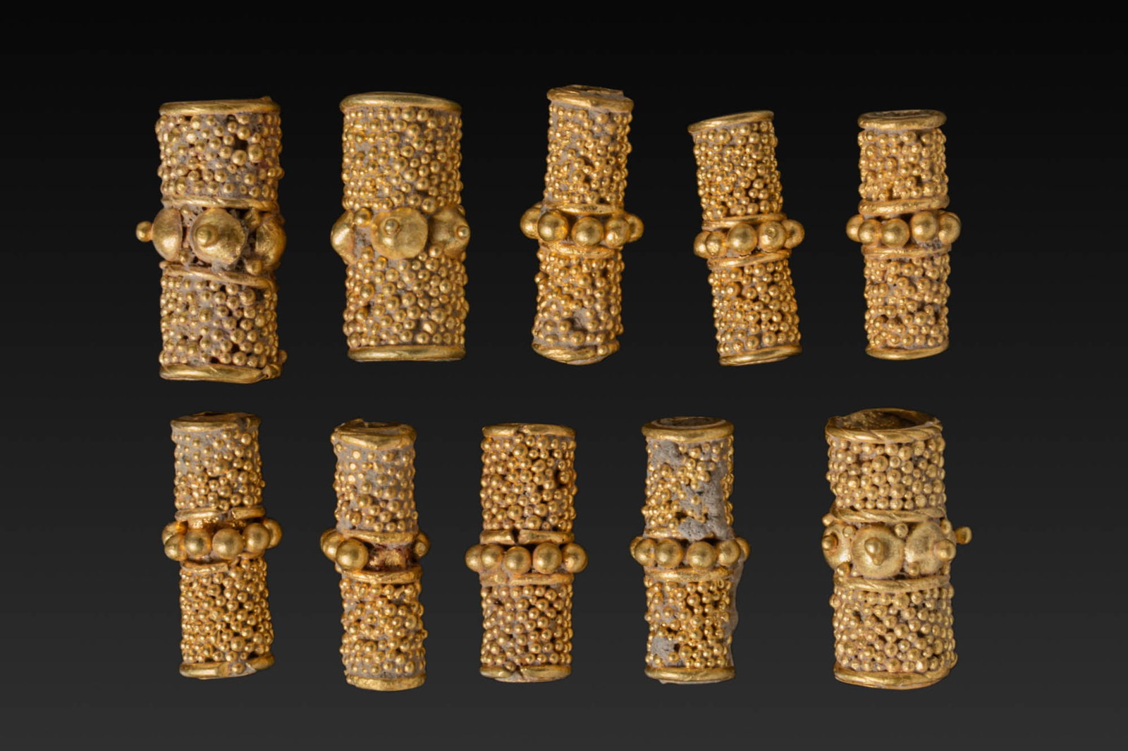 COLLECTION OF 10 HELLENISTIC HIGH KARAT GOLD TUBULAR BEADS WITH GRANULATION: Ca. 400 - 200 BC. A collection of 10 gold beads, each formed as a short tube with a central band of larger granules between plain collars repeated at the ends of the tube, the fields decorated with de