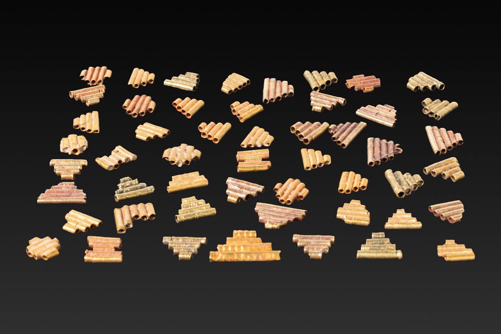 LARGE COLLECTION OF GREEK HIGH KARAT GOLD BEADS: Ca. 800 - 400 BC. A large collection of gold beads, each formed as a compact bundle of parallel hollow tubes with fine ribbing and occasional applied granules. Size: 5-7mm x 5-12mm; Weight: 11g Proven