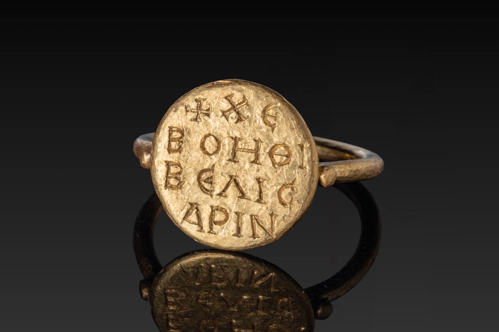 BYZANTINE HIGH KARAT GOLD INSCRIBED RING '______, ______ _________': Ca. AD 900 - 1100. A gold ring of slender, round-section hoop and applied circular bezel plate engraved with four lines of a Greek invocation. Size: D:18.14mm / US: 8 / UK: P 1/2; Weight: 6.7g Provena