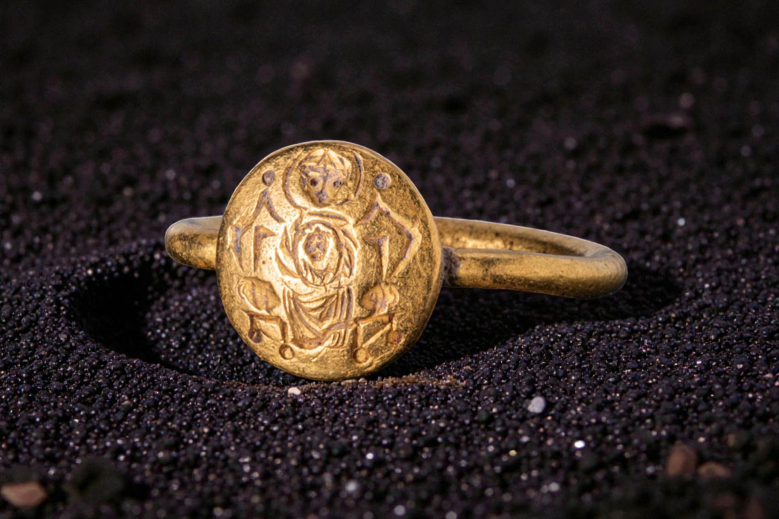 BYZANTINE HIGH KARAT GOLD RING WITH THE VIRGIN MARY AND CHILD: Ca. AD 500 - 700. A gold ring with a slender hoop of rounded section supporting a circular bezel engraved with the Virgin Mary enthroned and holding the Christ Child on her lap. For similar see: The M