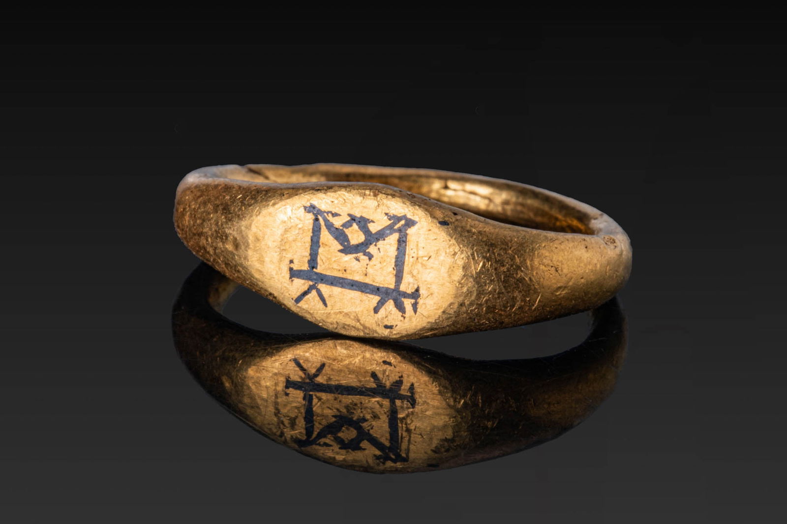 MEROVINGIAN HIGH KARAT GOLD RING WITH NIELLO MONOGRAM: Ca. AD 700 - 900. A gold signet ring with a rounded hoop of oval section, widening at the shoulders to a broad oval bezel plate with a complex niello monogram. For similar see: The British Museum, Mus