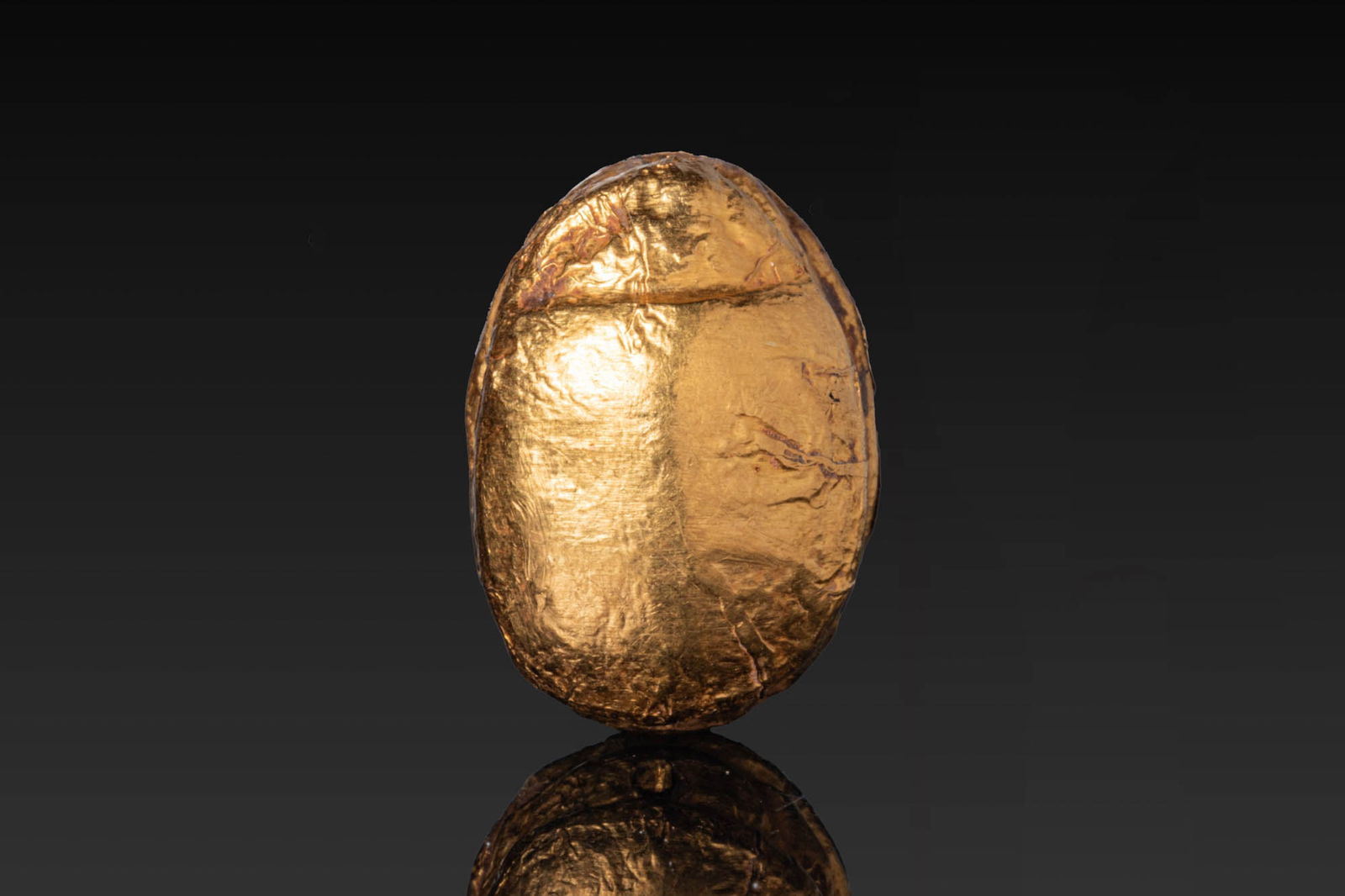 EGYPTIAN STONE AND GOLD LEAF SCARAB WITH QUADRUPED: Middle Kingdom, Ca. 2055 - 1790 BC. A stone and gold leaf scarab amulet with a rounded, smooth back, the pronotum separated from the elytra by a transverse groove. The flat underside is engraved with