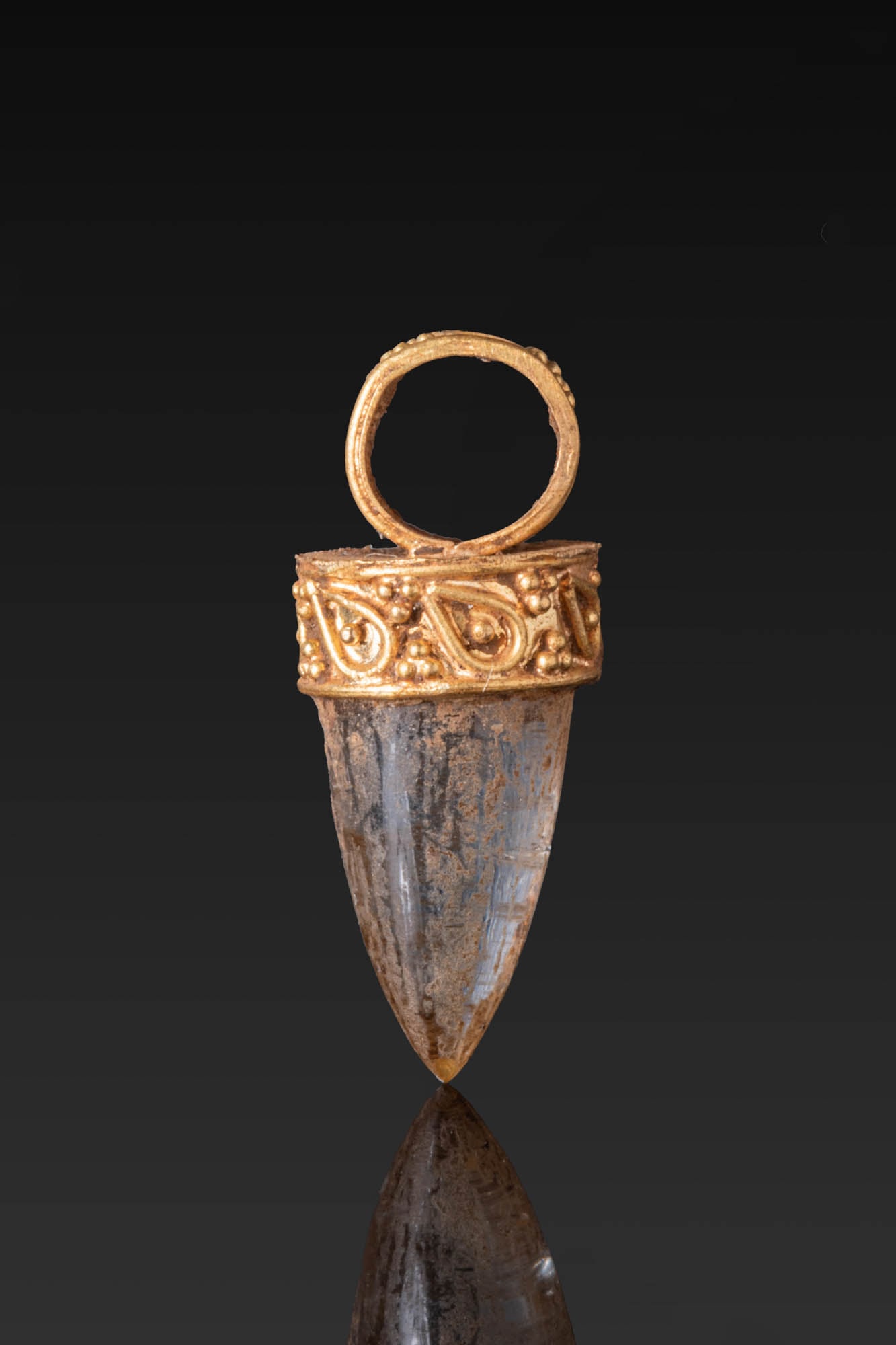 HELLENISTIC HIGH KARAT GOLD PENDANT WITH ROCK CRYSTAL: Ca. 300 - 100 BC. A gold pendant set with a tapered rock crystal drop in a circular mount with a plain upper plate, the collar and suspension loop decorated with granulation and drop-shaped motifs in