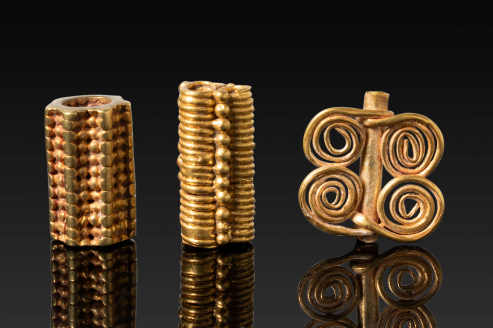 PETITE COLLECTION OF GREEK HIGH KARAT GOLD BEADS WITH GRANULATION AND PENDANT: Ca. 800 - 400 BC. A collection of three gold beads, including, from left to right: a cylindrical bead with applied granules arranged in tight, regular rows, with seven encircling granulated ridges; a