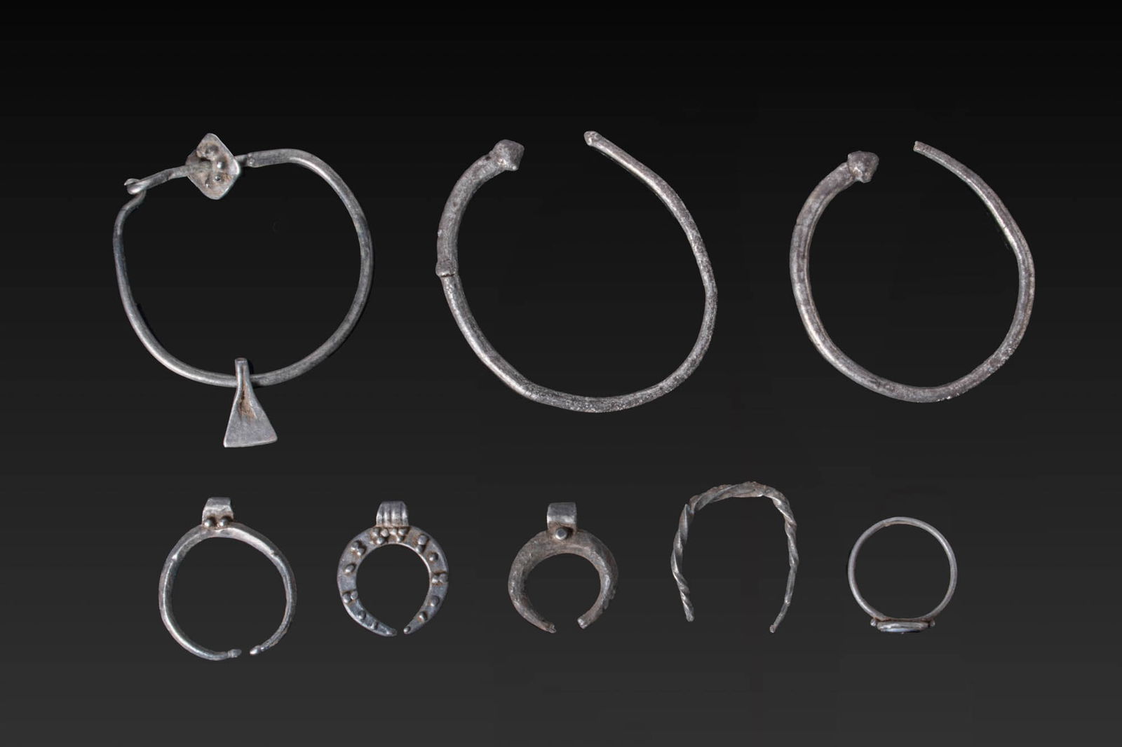 COLLECTION OF VIKING AND BYZANTINE SILVER JEWELLERY: Ca. AD 600 - 900. A collection of silver jewellery, including, from left to right (top row): a large hoop earring with a triangular pendant; a pair of hoop earrings, each with a rounded knop terminal