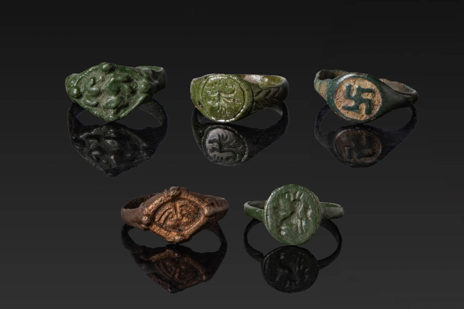 COLLECTION OF VIKING BRONZE RINGS: Ca. AD 1200 - 1400. A collection of five bronze rings, including, from left to right: a ring with a rhomboid-shaped bezel and a low-relief central motif; a signet ring with a circular, incised bezel a