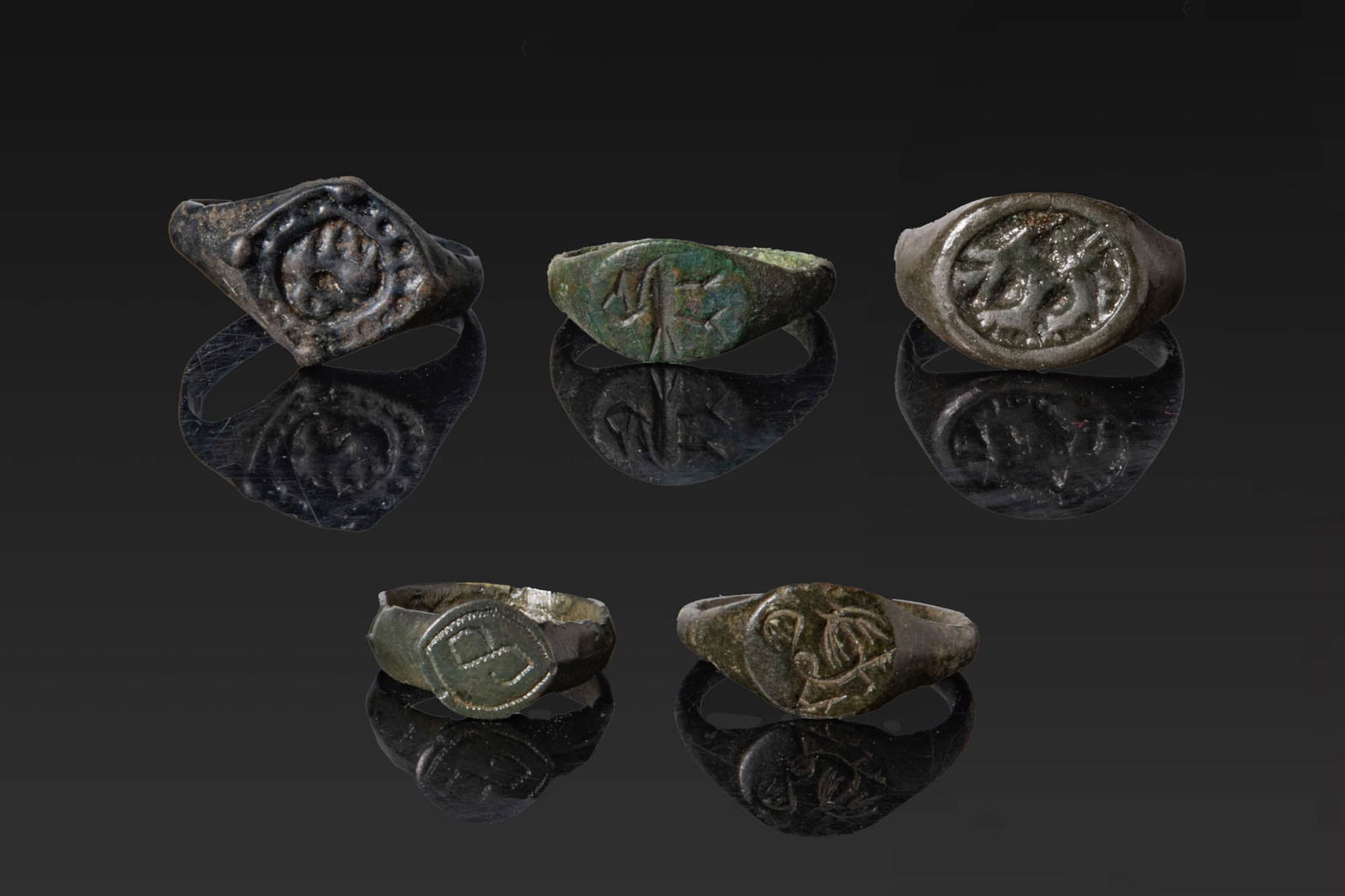 COLLECTION OF VIKING PERIOD BRONZE RINGS: Ca. AD 800 - 1200. A collection of five bronze rings, including, from left to right: a ring with a lozenge-shaped bezel with a stylised animal within a dotted border; a ring with an oval bezel engrave