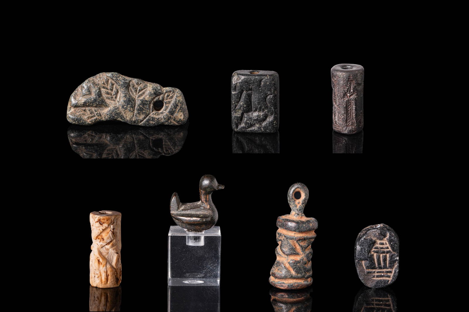COLLECTION OF MIDDLE EASTERN SEALS AND PENDANTS: Ca. 3rd - 1st millennium BC. A collection of seals and amulets, including, from left to right: an irregular stone plaque seal, pierced for suspension and carved with a radiating leaf pattern; a rectan