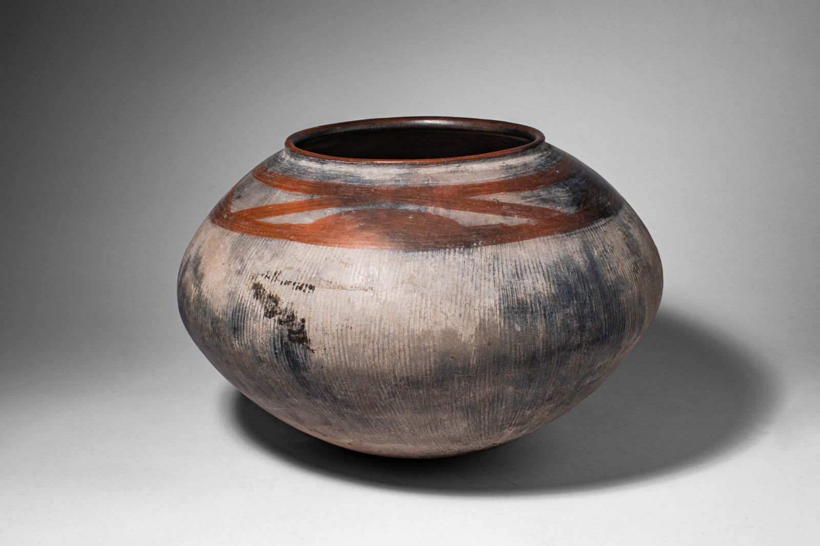 TANZANIA NYAKUSA TERRACOTTA POT: Ca. late 19th - 20th century AD. >A terracotta pot of globular form with a short open neck and rounded body, the surface finely burnished and decorated with sweeping bands of reddish-brown slip