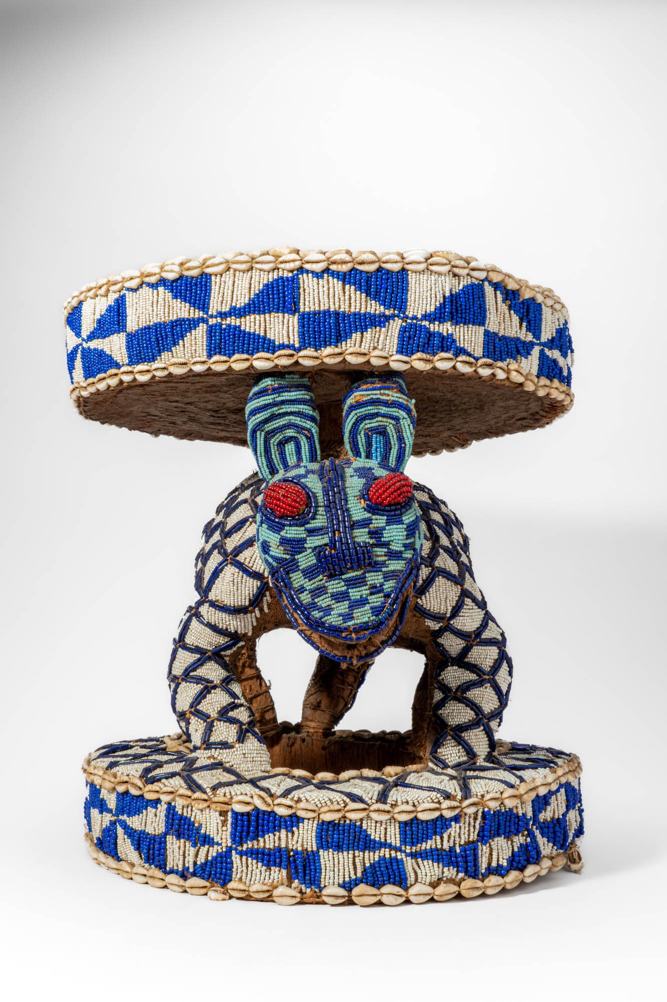 CAMEROON BEADED STOOL IN THE FORM OF A LEOPARD, BALI CHIEFDOM: Ca. 19th century AD. >A ceremonial beaded stool in the form of a leopard, the animal crouched beneath a circular seat and supporting it with four bent legs. The sculpture is entirely covered with dens