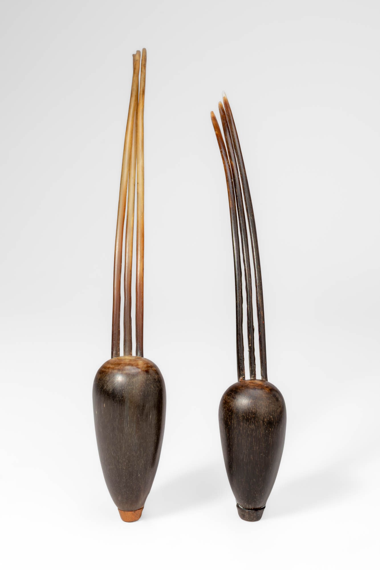 PAIR OF SNUFF CONTAINERS: Ca. 20th century AD. >A pair of snuff containers composed of carved shell bodies fitted with slender horn prongs forming elongated stoppers. Each vessel features a smooth, tapering form with a