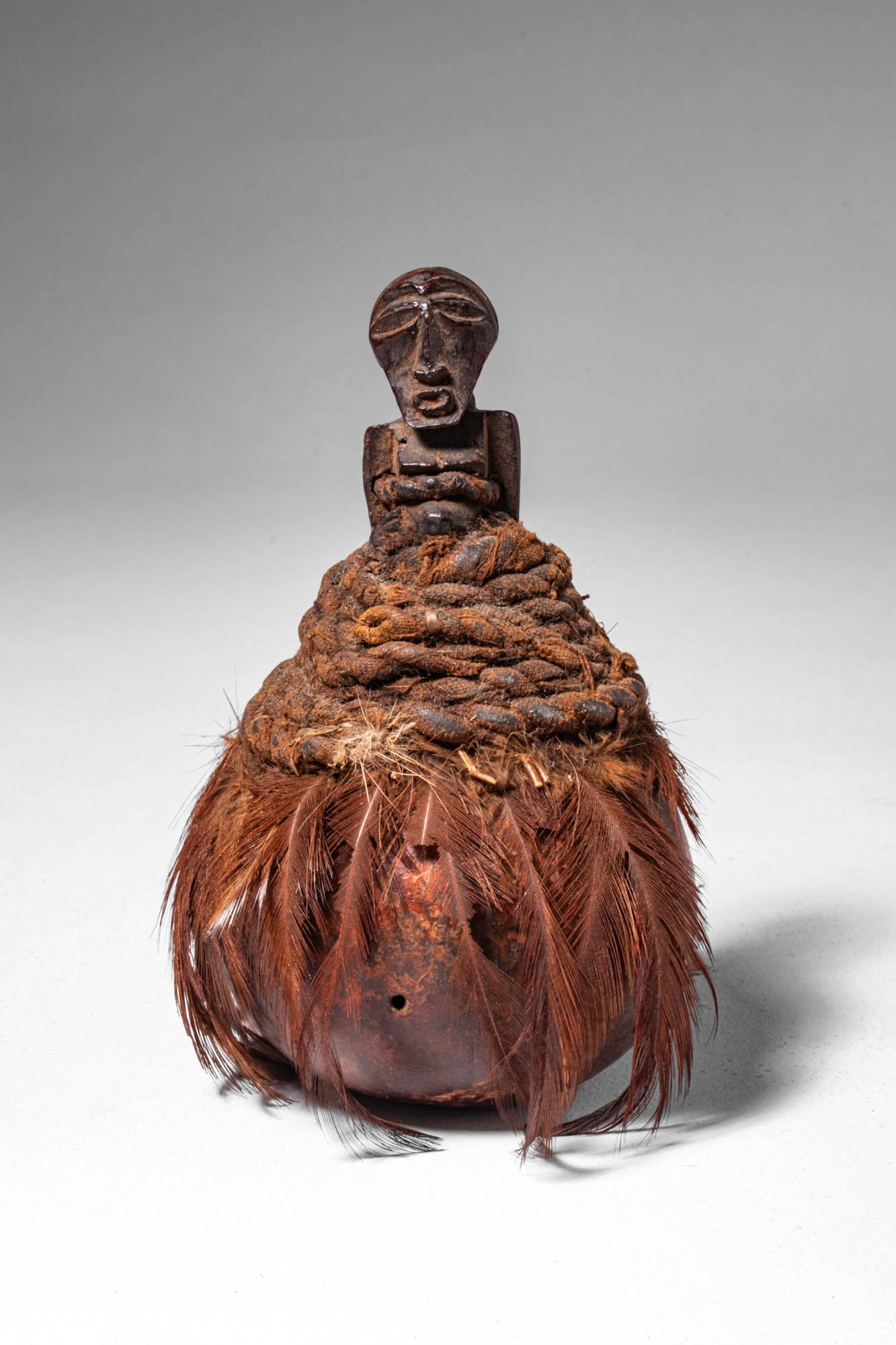 BEMBE TRIBE CALABASH WITH PROTECTIVE FETISH STOPPER: Democratic Republic of Congo, Ca. 19th - 20 th century AD. >A fine calabash vessel in gourd form fitted with a carved wooden stopper in the form of a stylised human figure. The neck is wrapped with co