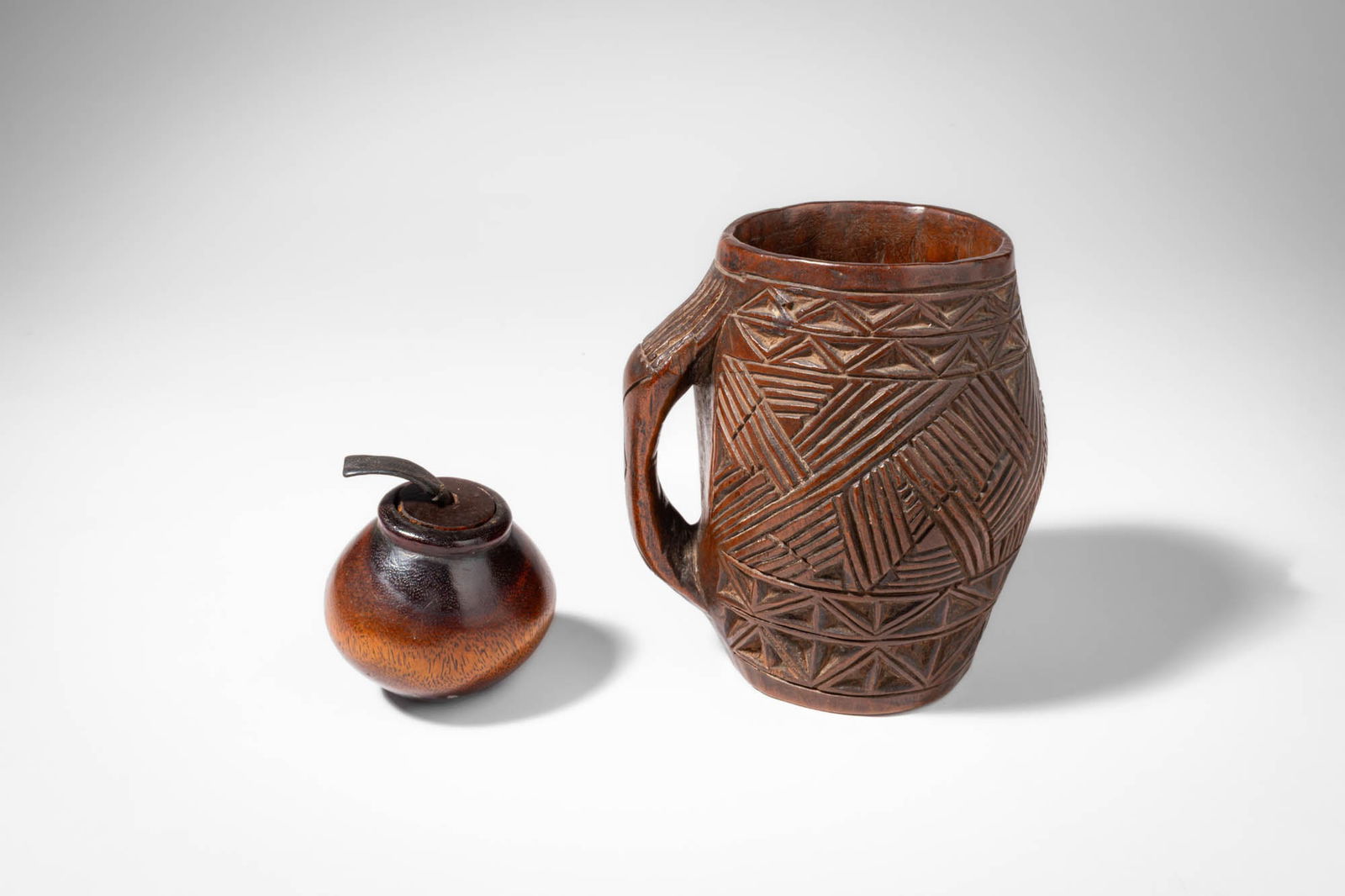 MALI CONTAINER AND KUBA CUP: Ca. 20th century AD. >A small globular wooden pot from Mali, possibly Dogon or Bambara, with a fitted lid and leather thong handle; together with a carved wooden cup or vessel with a side handle, Kuba