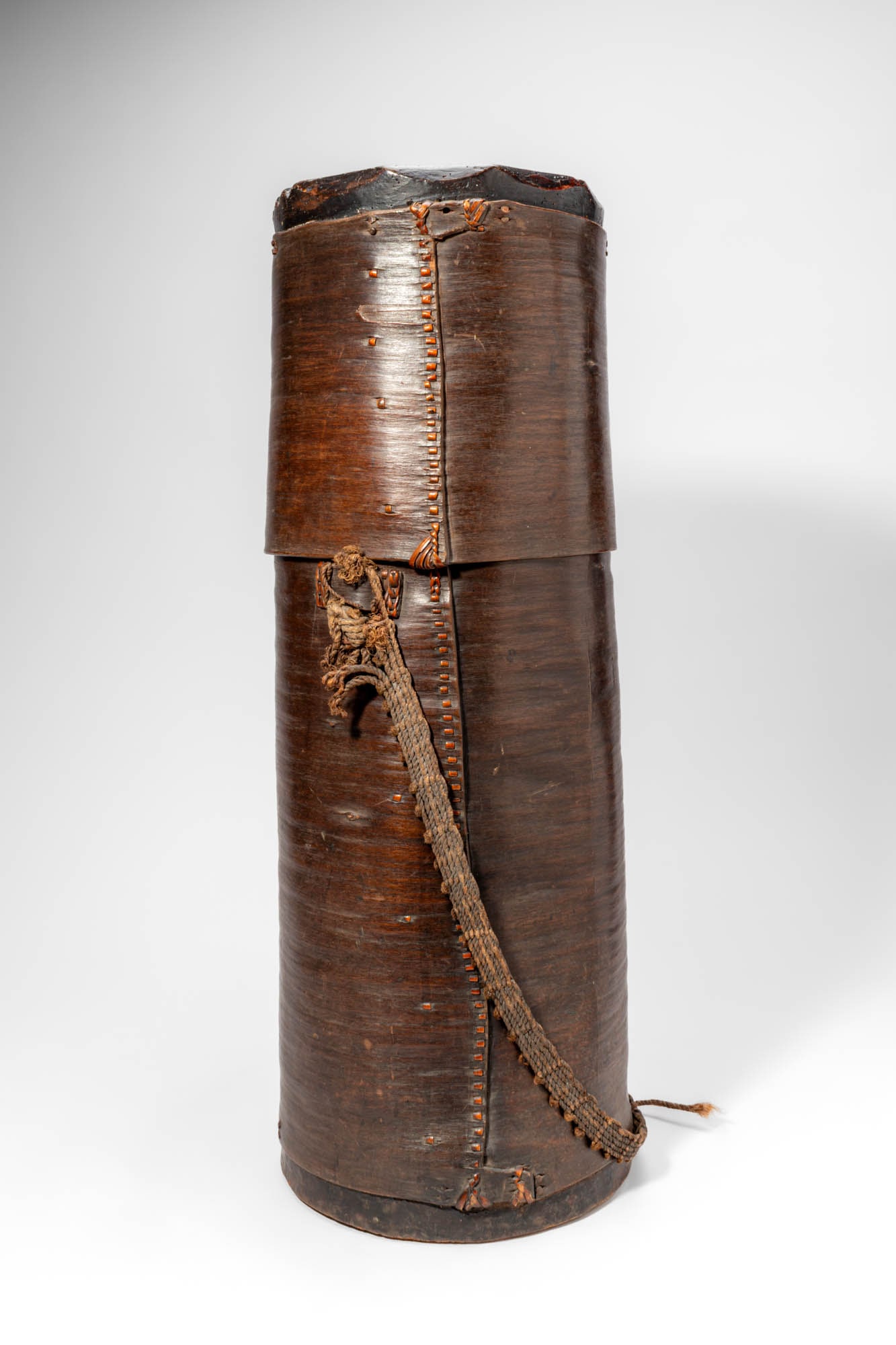 MANGBETU HONEY BARK BOX: Ca. 20th century AD. >A cylindrical Mangbetu honey container constructed from sheets of bark carefully shaped into a tall tubular form and secured along the vertical seam with stitched fibre binding.