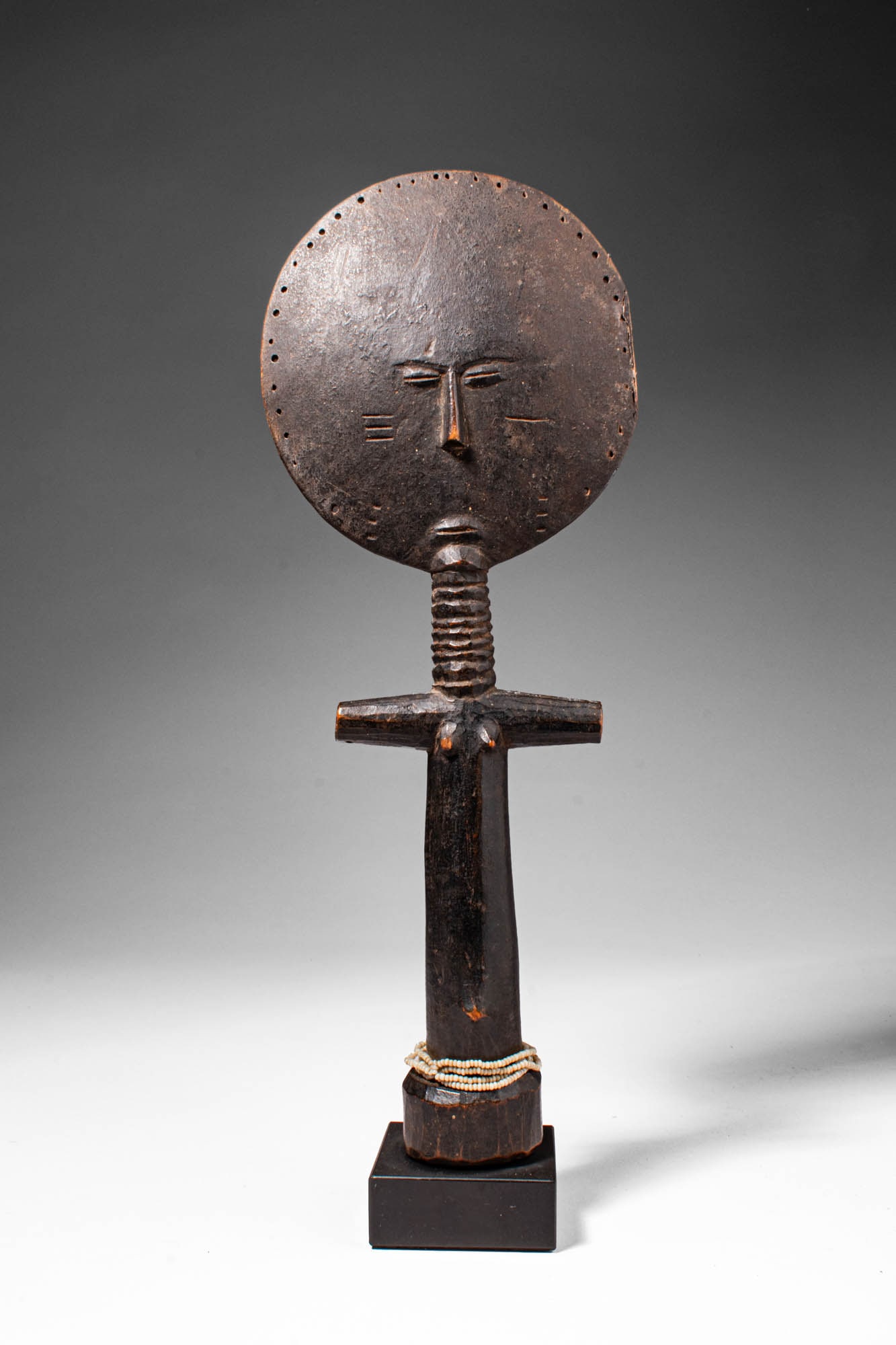 AKAN AKUA'BA DOLL: Ca. 19th - 20th century AD. >A wooden Akua'ba doll carved in the characteristic form, the figure is defined by a large circular head above a slender cylindrical body with short horizontal arms. The fa