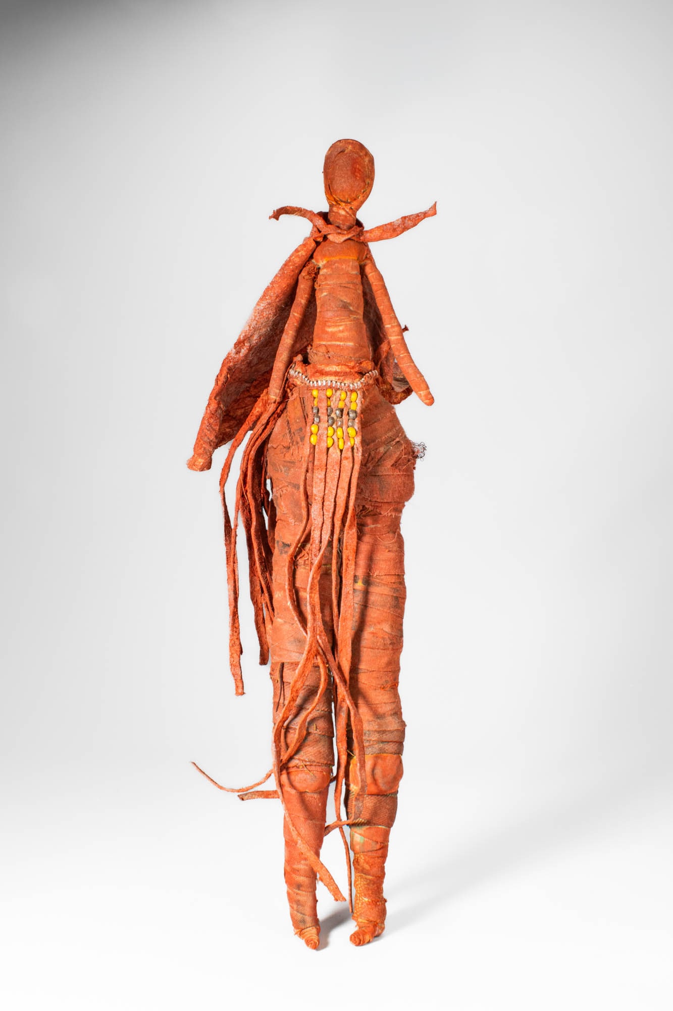 AFRICAN CLOTH DOLL: Ca. 20th century AD. >An African doll made from wrapped cloth forming a slender standing figure with elongated proportions, the doll features a small head with a narrow neck and simplified facial form