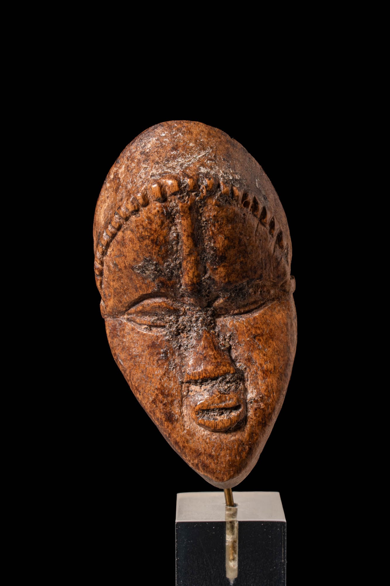 DAN MASK, IVORY COAST: Ca. 19th - mid 20th century AD. A Dan mask carved from a single piece of dense, reddish-brown wood, exhibiting the characteristic elongated oval face, full lips, and almond-shaped eyes with finely inc