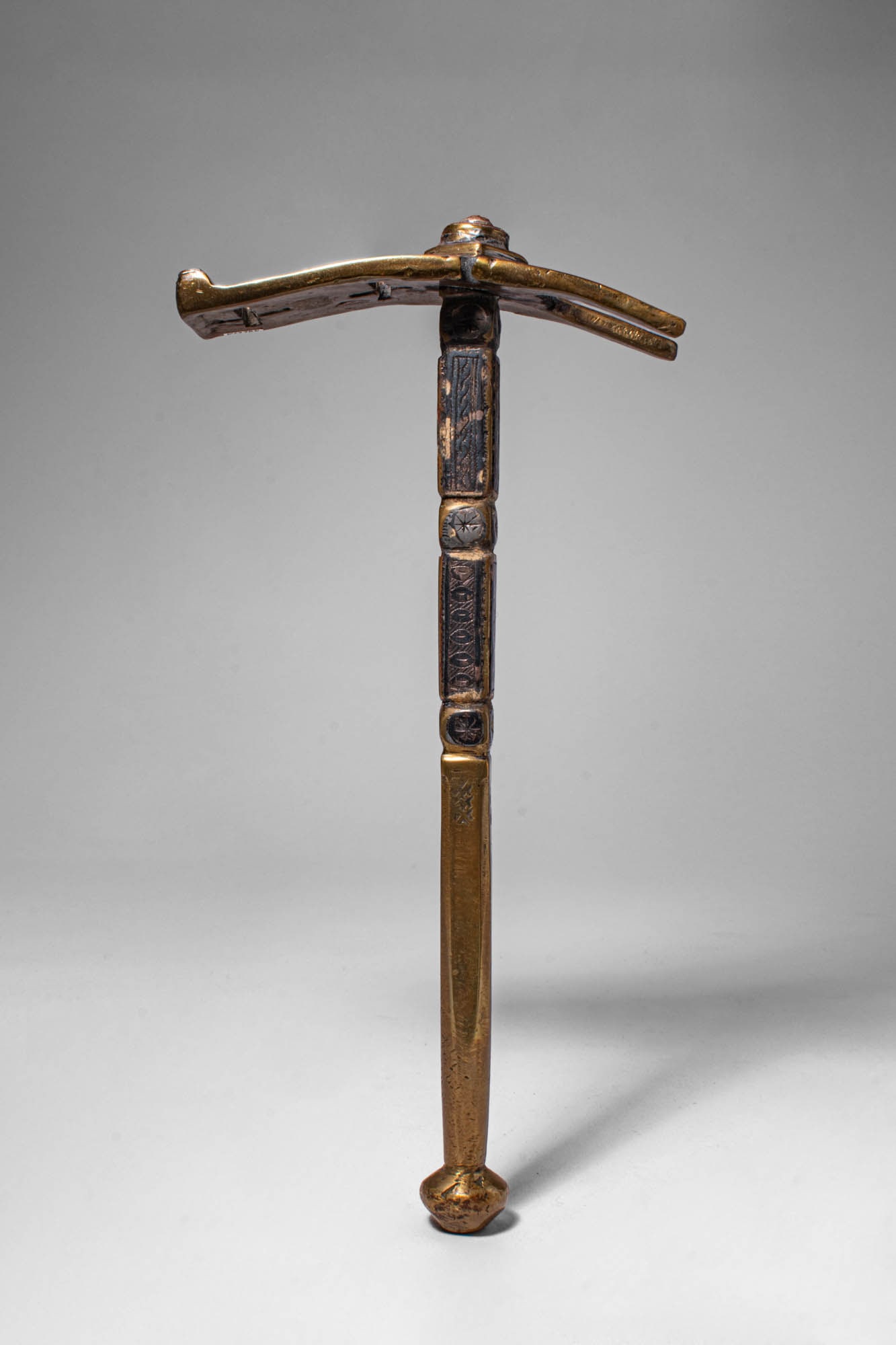 TUAREG HAMMER: Ca. 20th century AD. >A Tuareg hammer with a curved double-ended head mounted on a slender shaft, the hammer features engraved decorative panels along the handle, including geometric motifs typical of